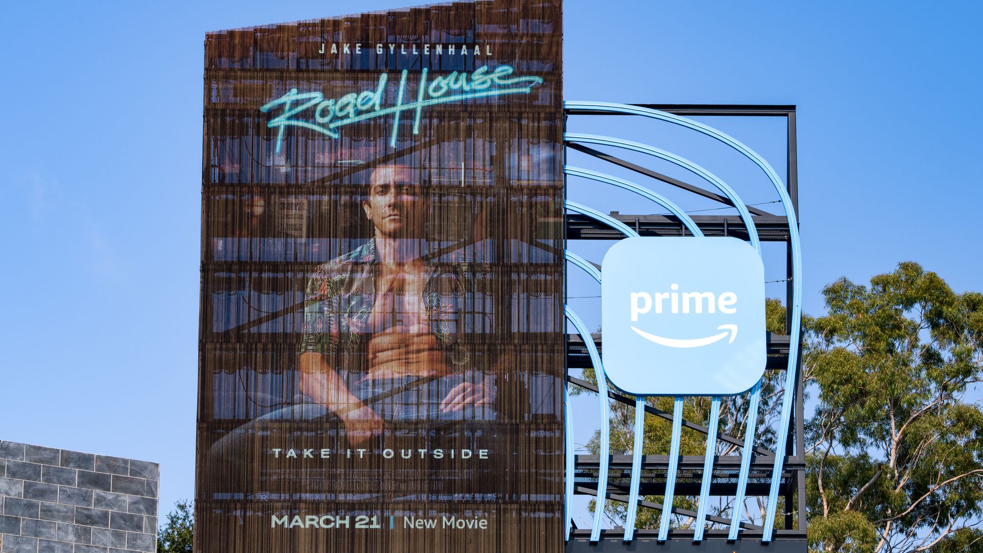 A billboard with "Road House" in big letters and a photo of Jake Gyllenhaal.