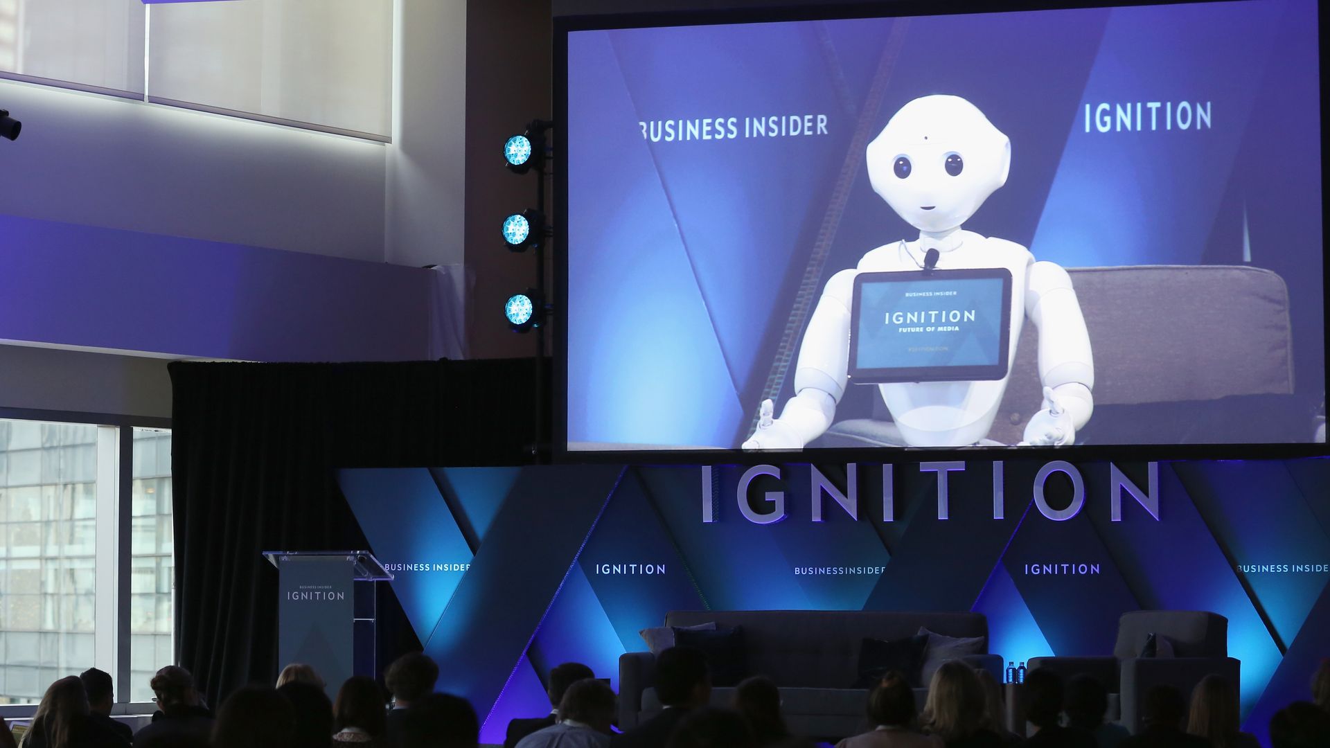 A robot is shown on a screen at a conference