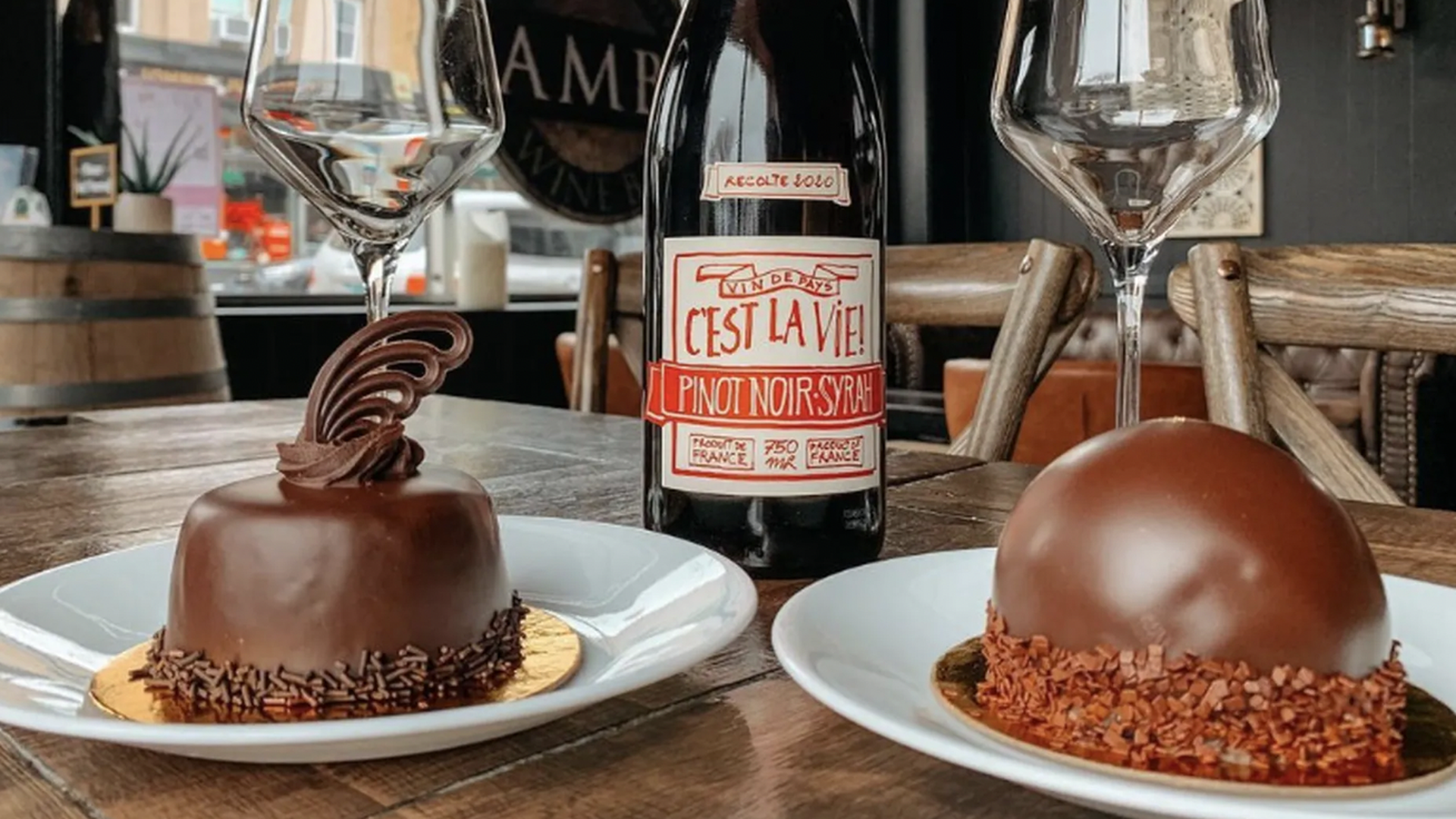 two chocolate cakes with a bottle of red wine