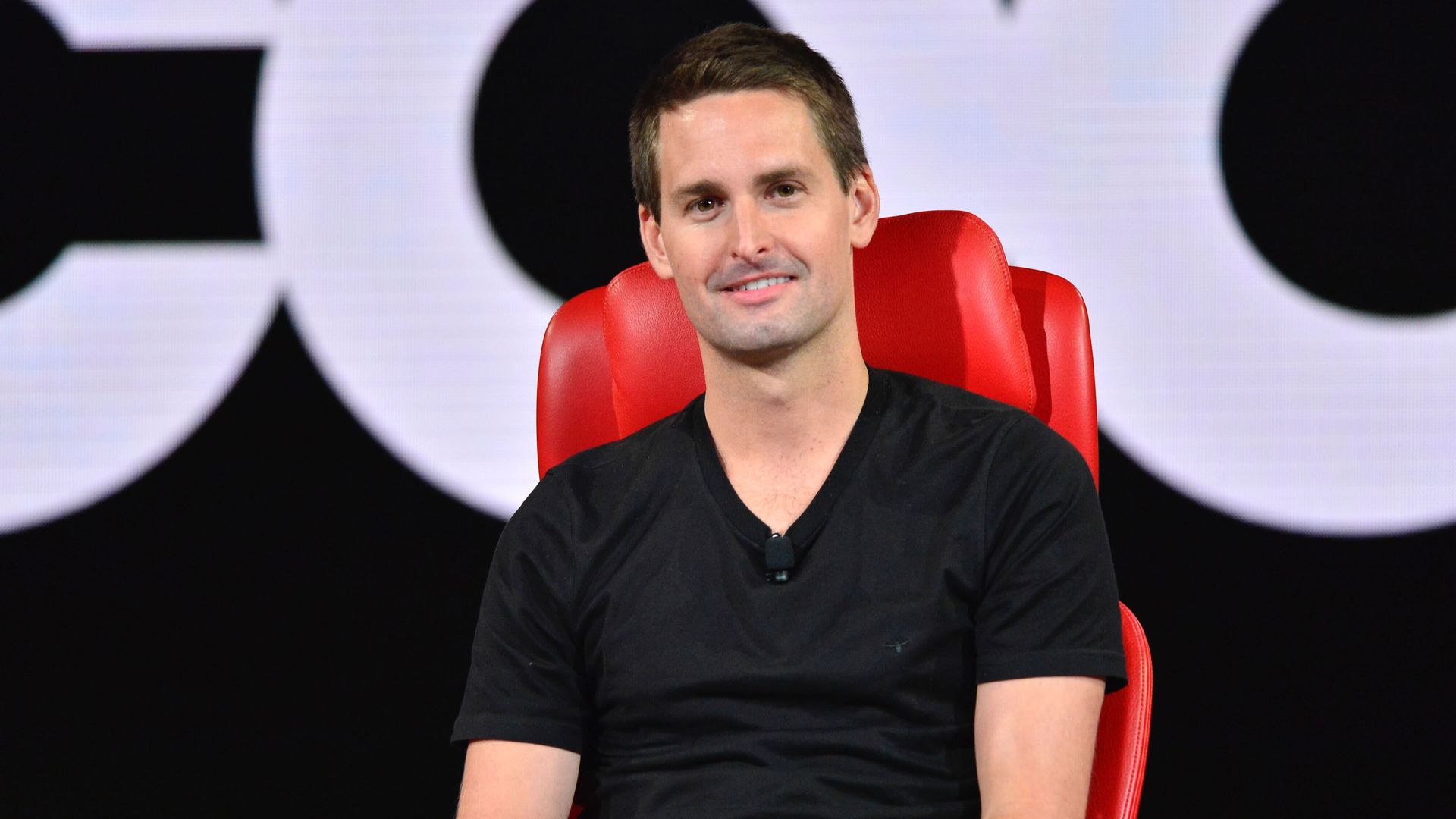 Photo of Evsn Spiegel sitting in a red chair with a black t-shirt