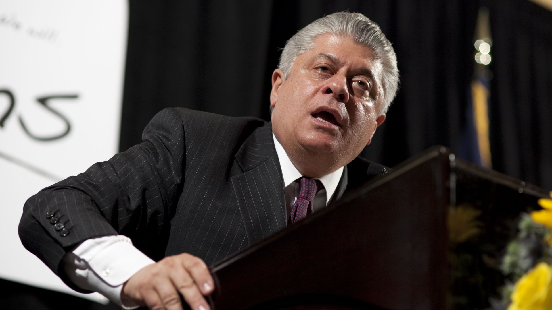 In this image, Andrew Napolitano leans over a podium and speaks at a crowd. 