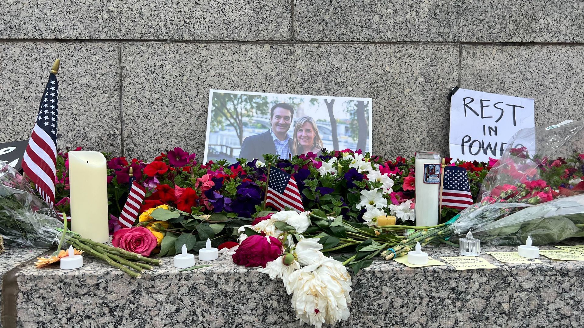 A tribute to hortman outside the capitol with flowers candles, a photo and a rest in power sign