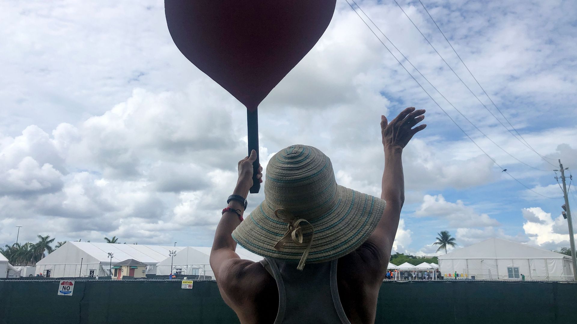 A woman holds a sign in the shape of a heart in front of a child migrant detention center