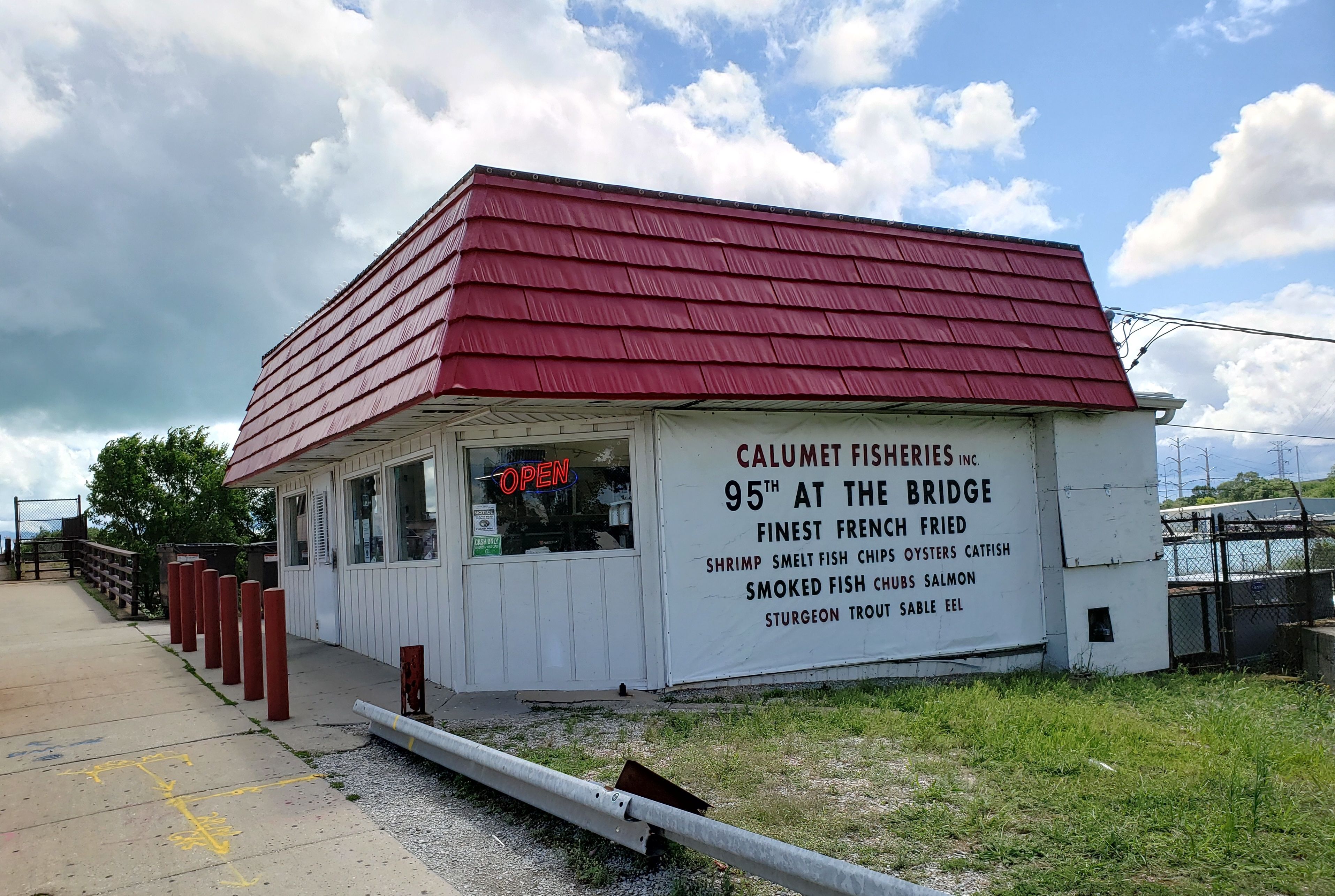 White shack with red roof that reads Calumet Fisheries.