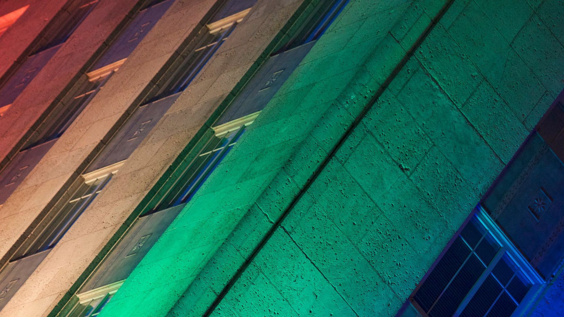 Photo of rainbow colors projected on a building. 