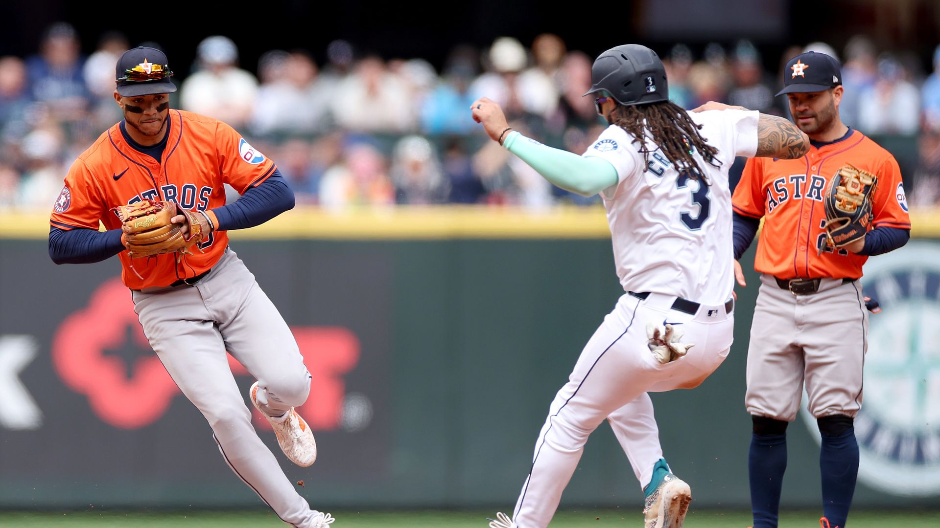 A baseball player in white is out at base when a player in orange catches the ball.