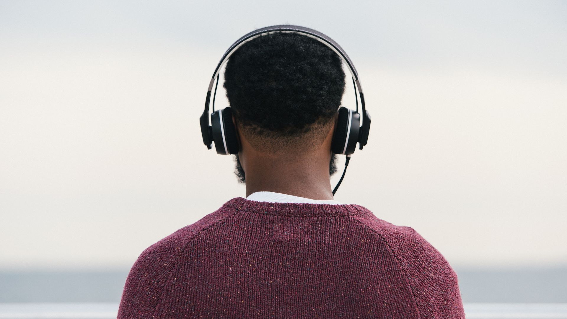 A man listens to music facing a beach
