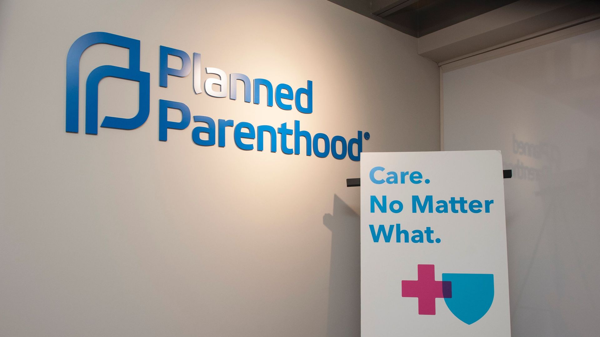 Photo of a wall with the Planned Parenthood logo and a sign that says "Care. No Matter What."