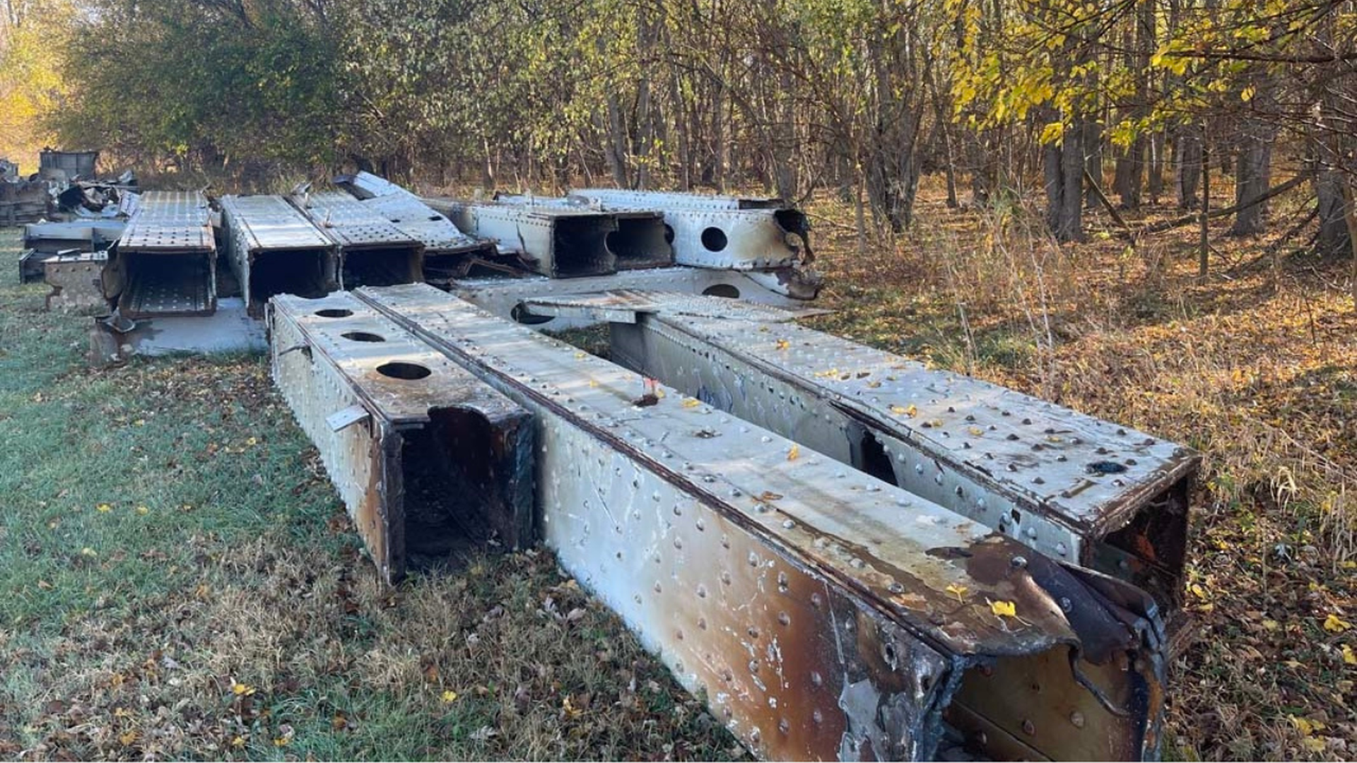 Charred steel beams from the previous Buck O'Neil bridge lie in a grassy field after demolition.