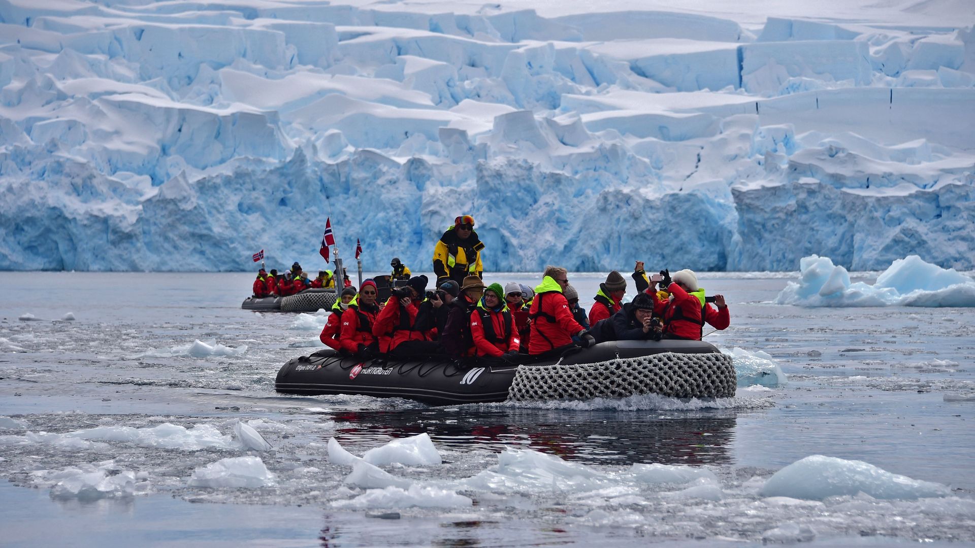 In this image, a large group of people sit in a boat on ice water in the Antarctic