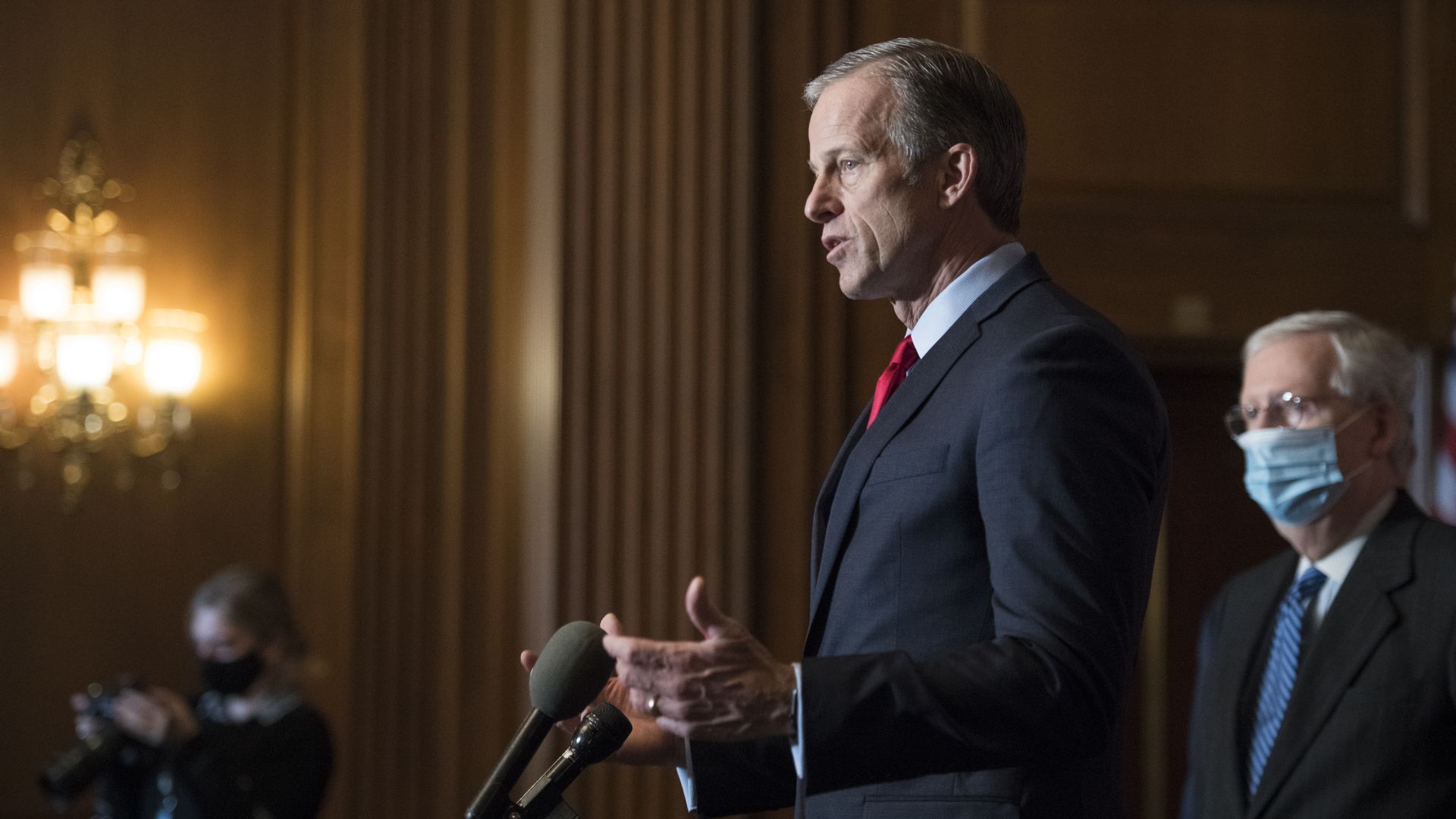 Picture of John Thune speaking into a microphone while Mitch McConnell stands in the background