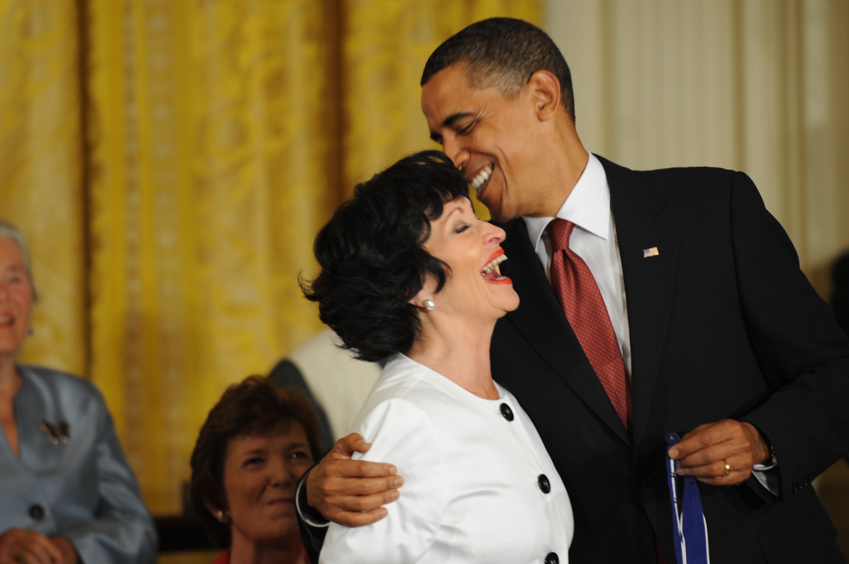 Chita Rivero laughs while President Barack Obama whispers in her ear.
