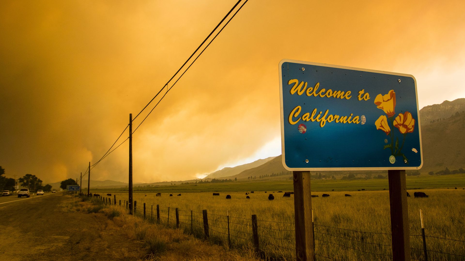 Photo of sign in front of a wildfire in California