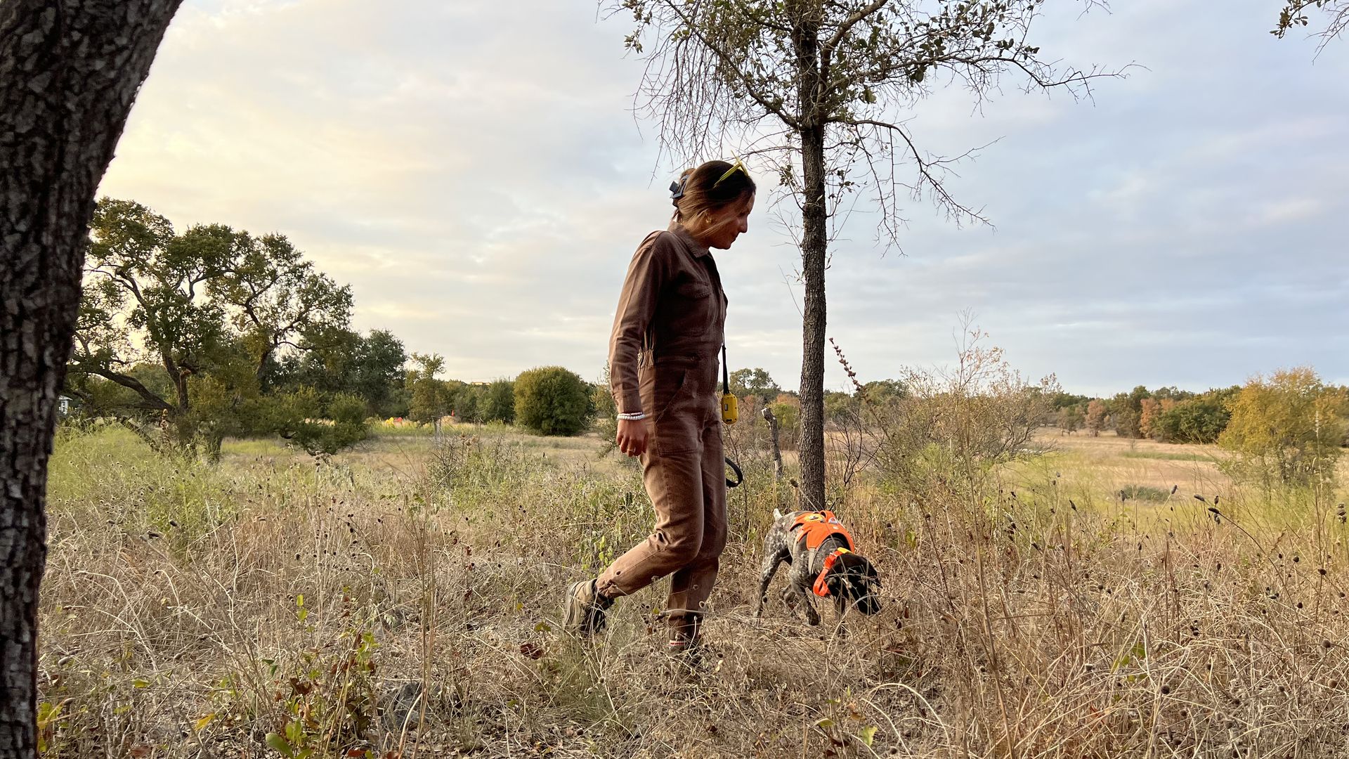 A photo of a woman and a dog in a field.