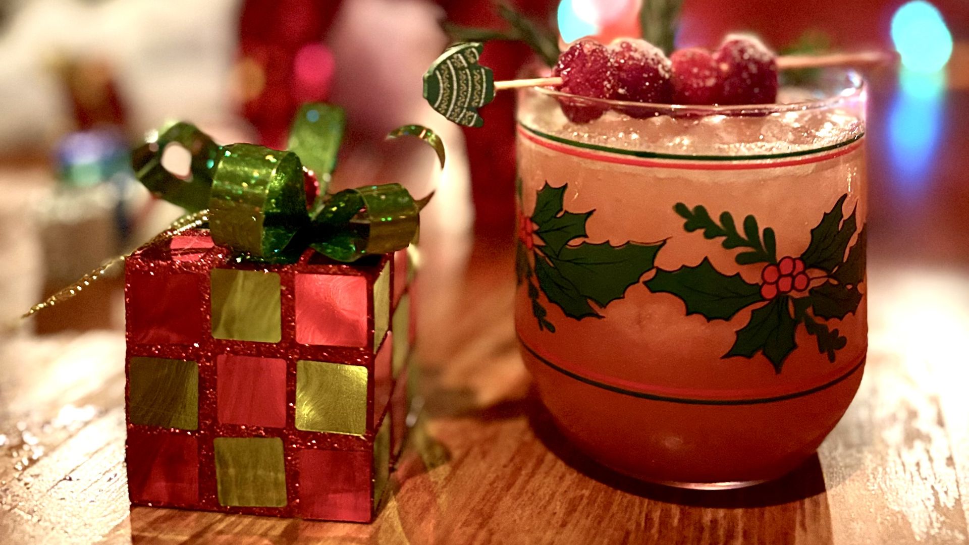 A photo of a present-wrapped rubix cube and a cranberry cocktail.