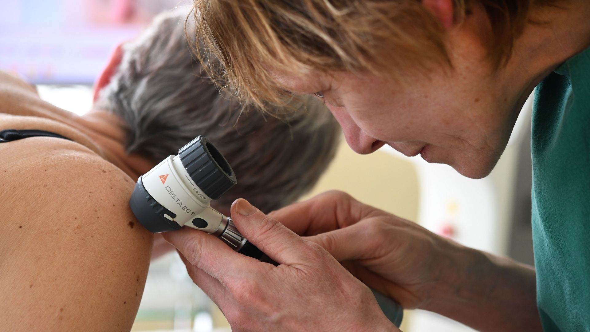 A dermatologist examines a patient
