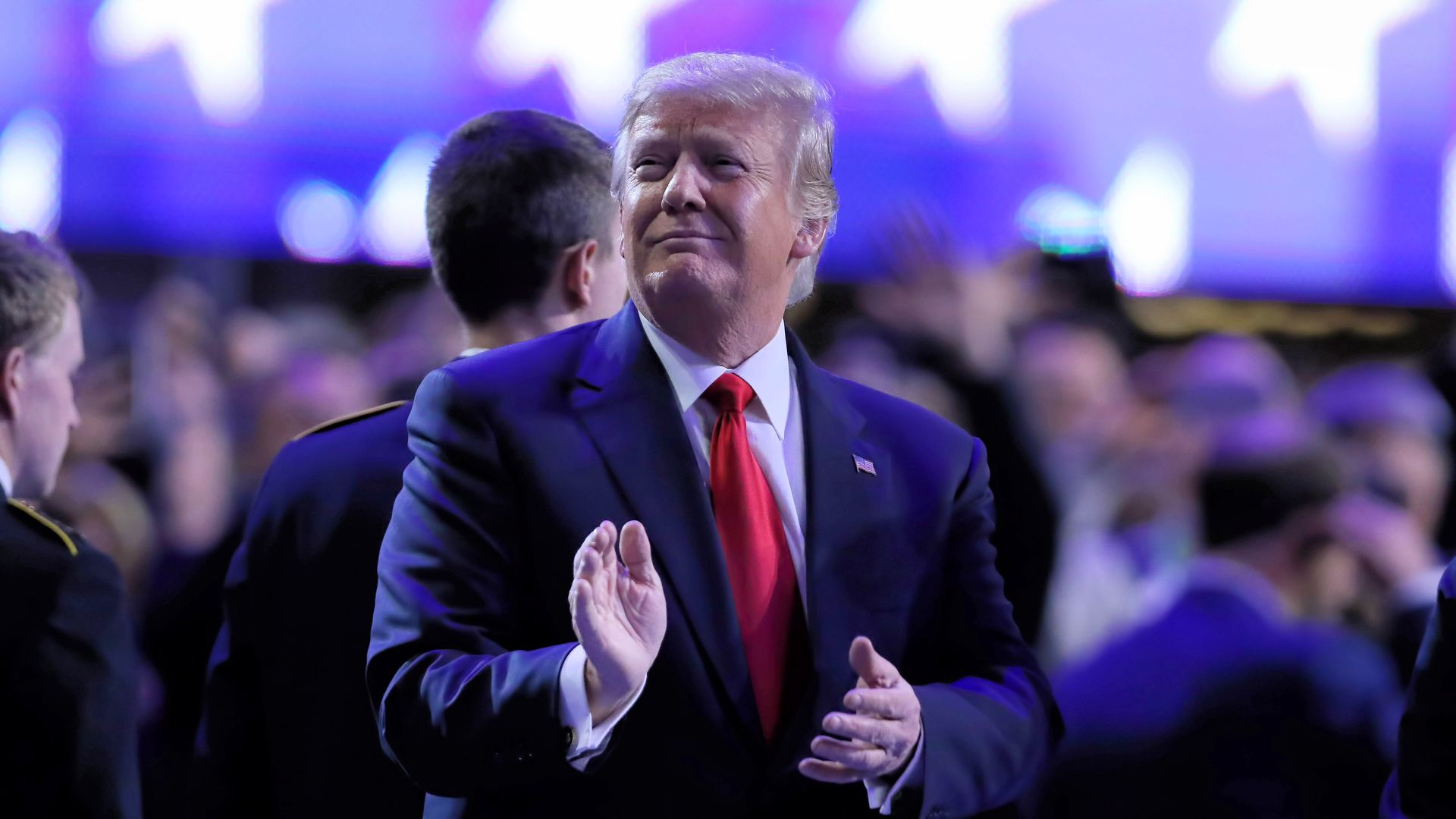 Donald Trump clapping his hands looking into the crowd from the ground floor of an event