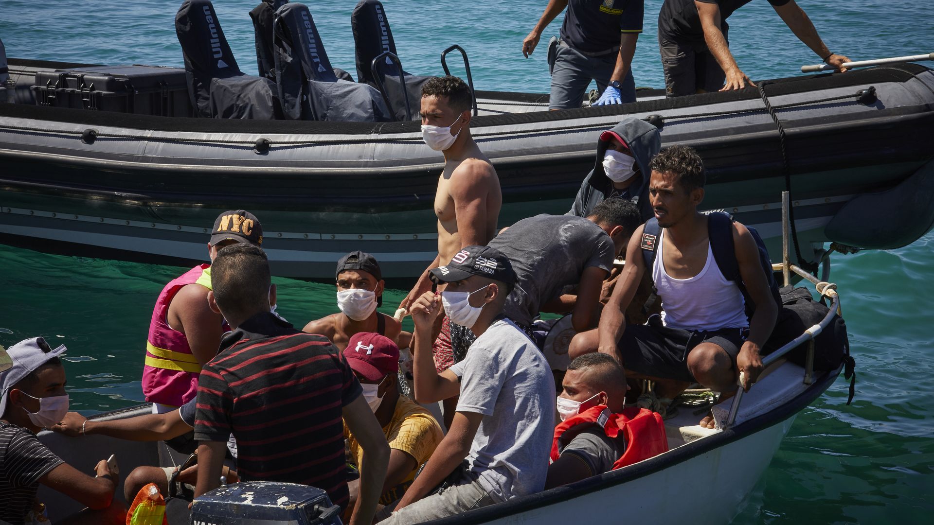  A group of migrants wait in their boat before being checked by medical staff on August 28, 2020 in Lampedusa, Italy.