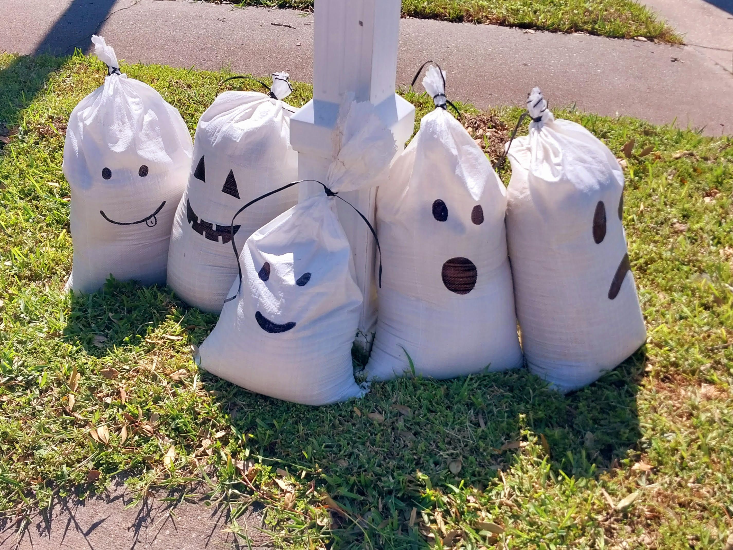 Five white sandbags with jack-o-lanter-style faces painted on them.