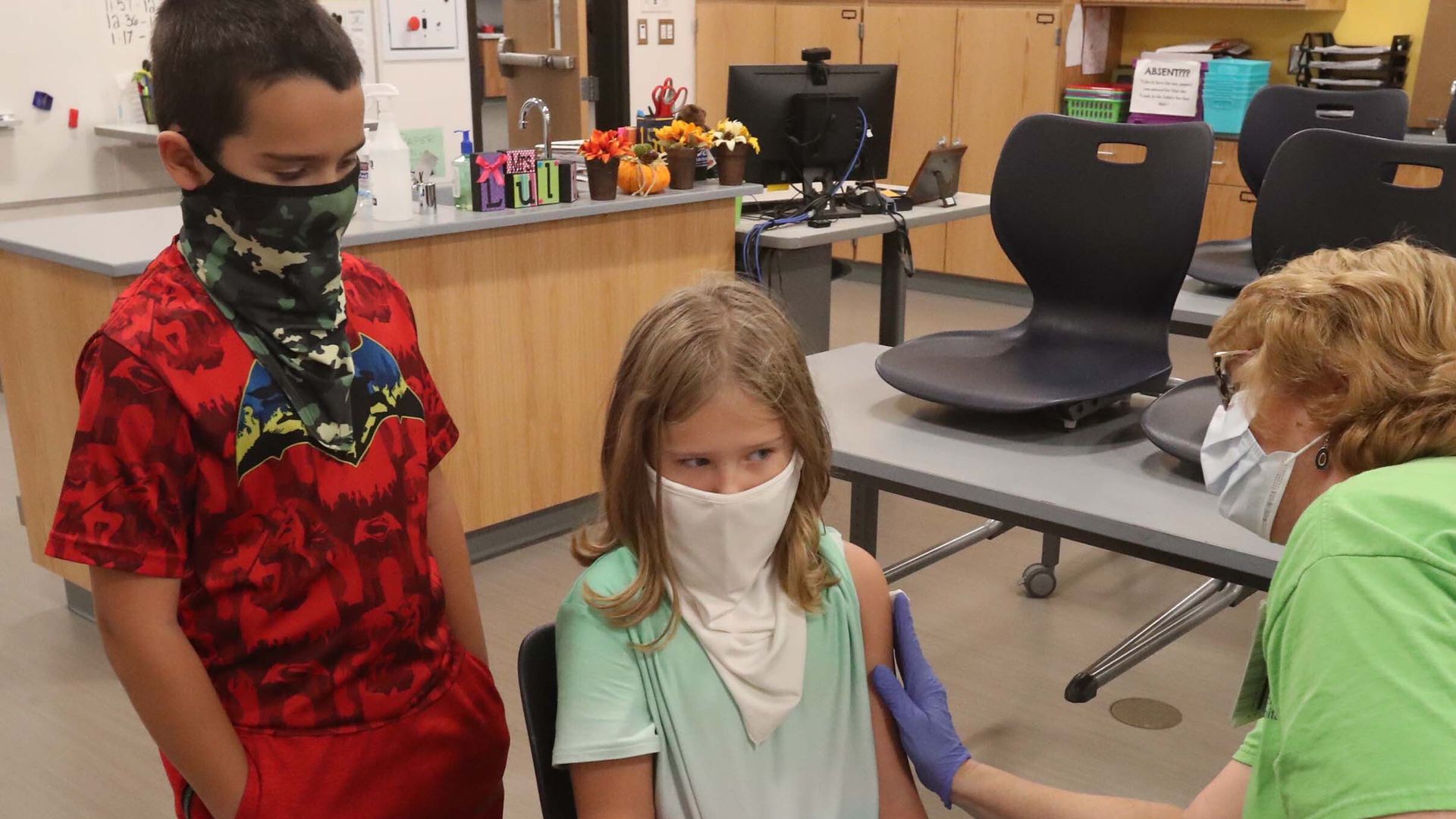 Twins Jake and Ella Benson, 8, get COVID shots this week from nurse Vickie Webb at their middle school in Akron, Ohio. 