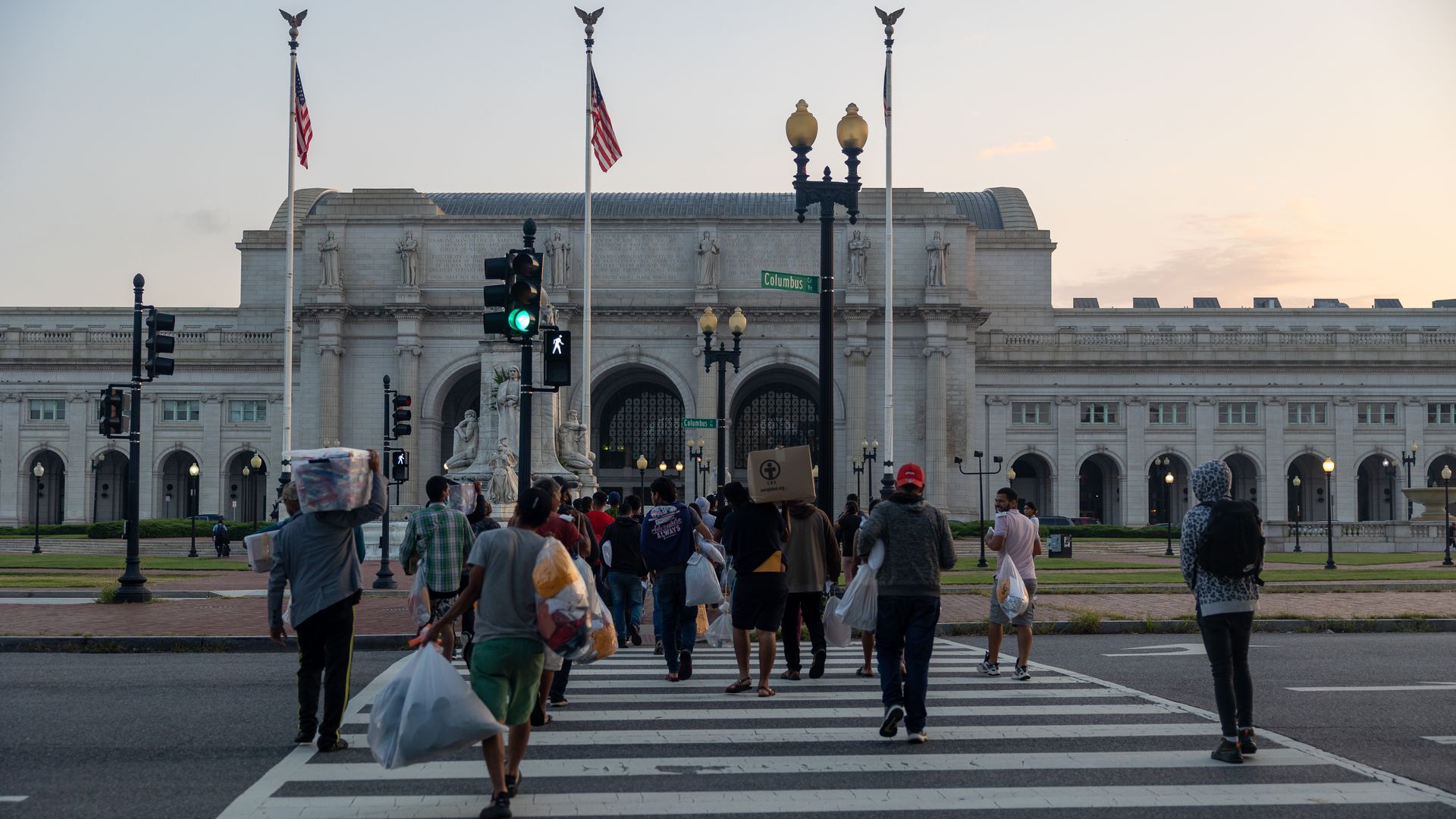 Immigrants who were sent to D.C. on buses from the southern border walk toward Union Station in D.C.