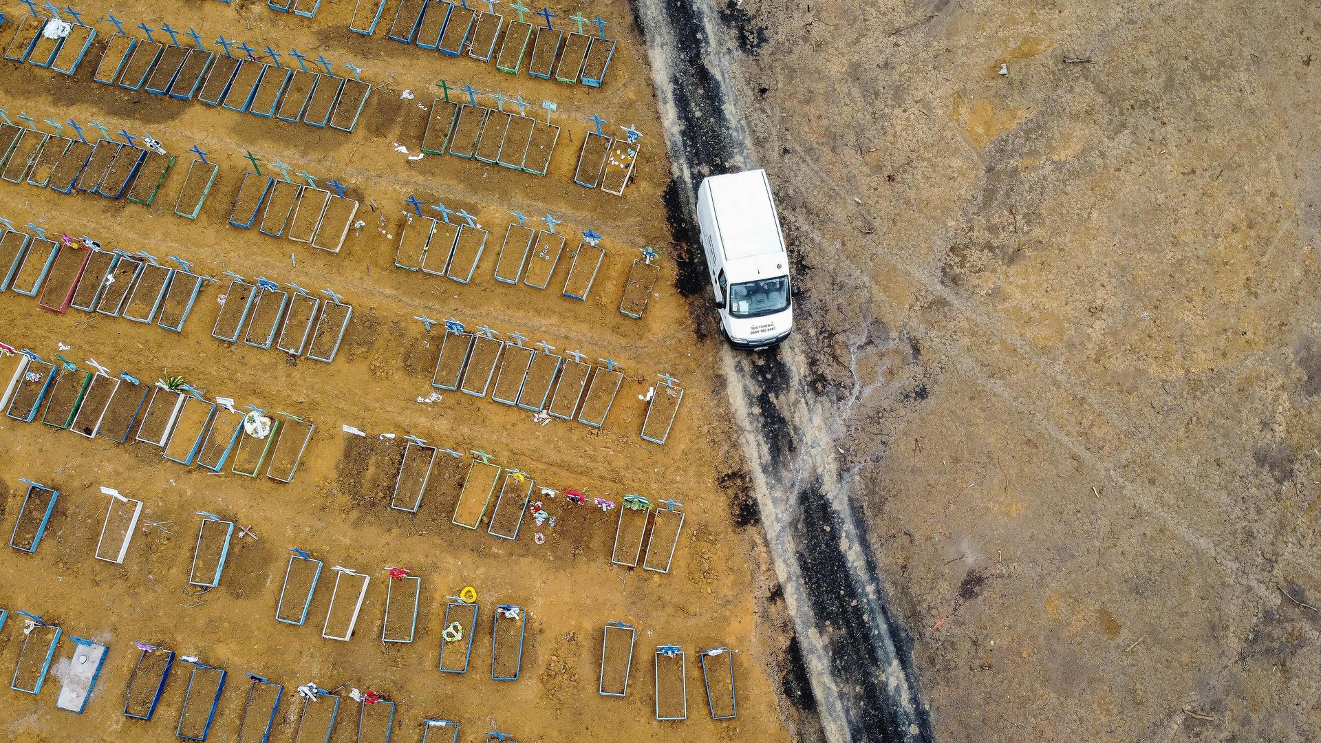 Birds-eye view of rows of graves as a truck drives by 