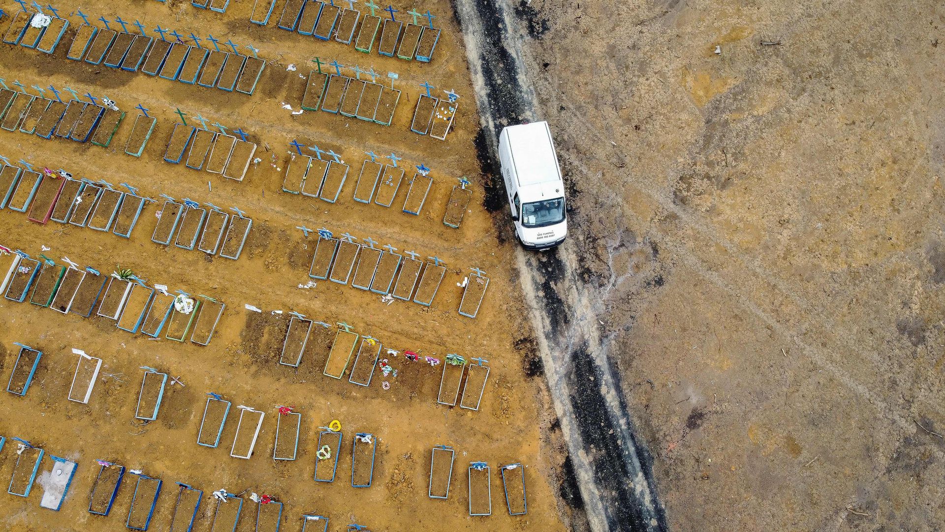 Birds-eye view of rows of graves as a truck drives by