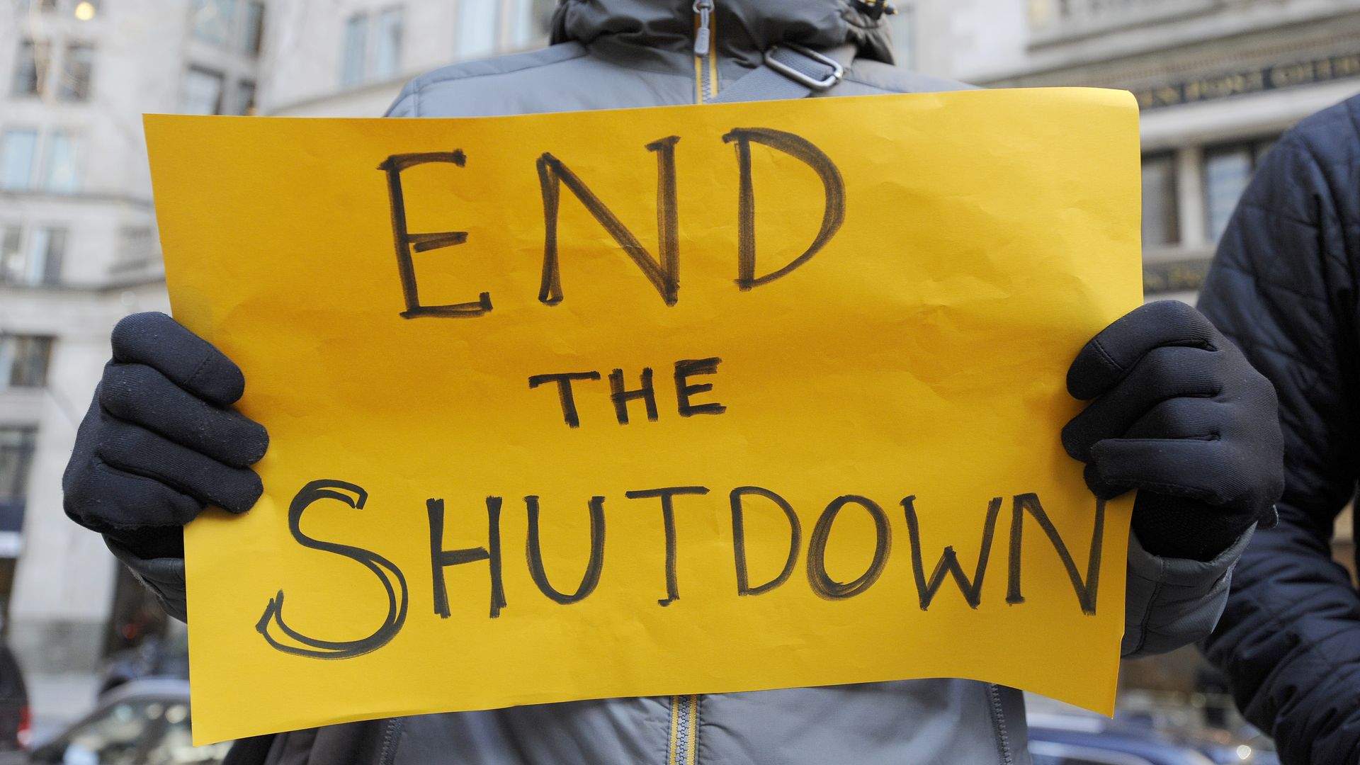 Sign reads "END THE SHUTDOWN."