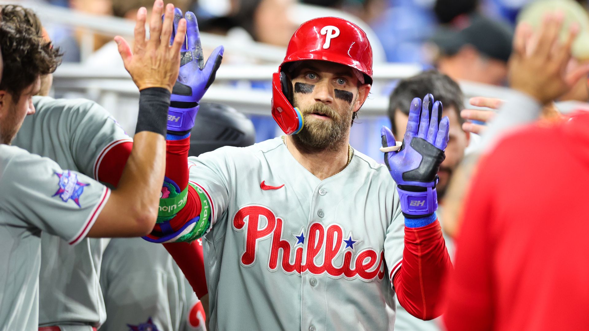 Phillies slugger Bryce Harper high-fives teammates after hitting a home run against the Miami Marlins.