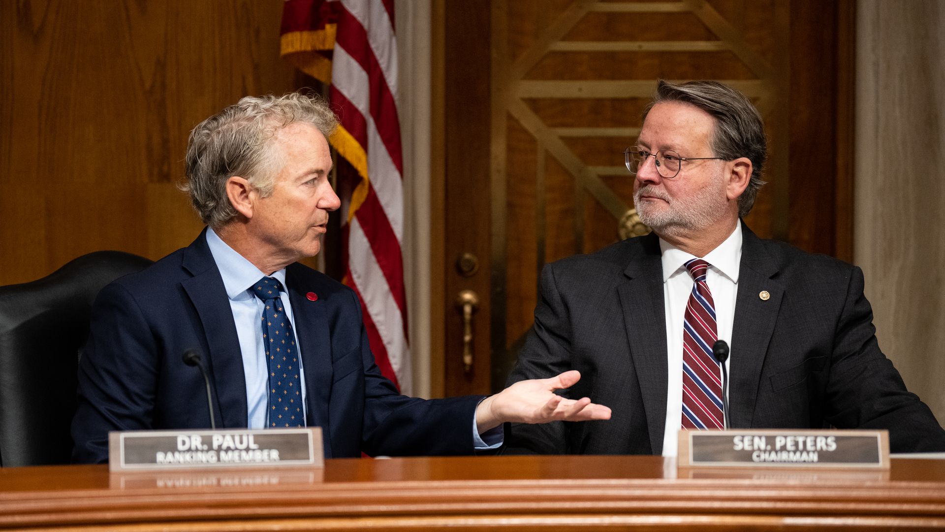 A photo of Sens. Rand Paul and Gary Peters at a dais.