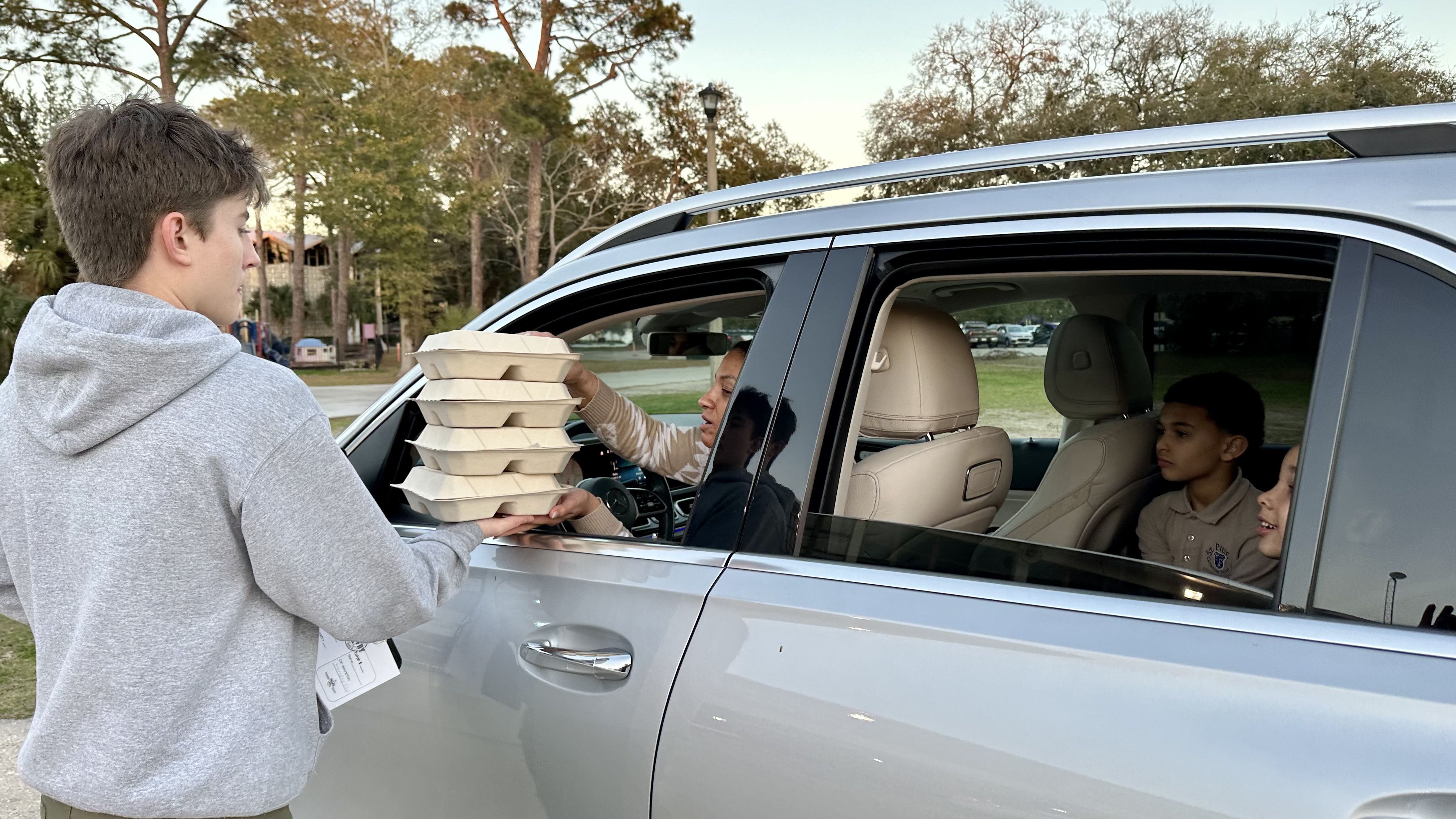 Photo shows a Boy Scout delivering boxes to a drive-thru customer.