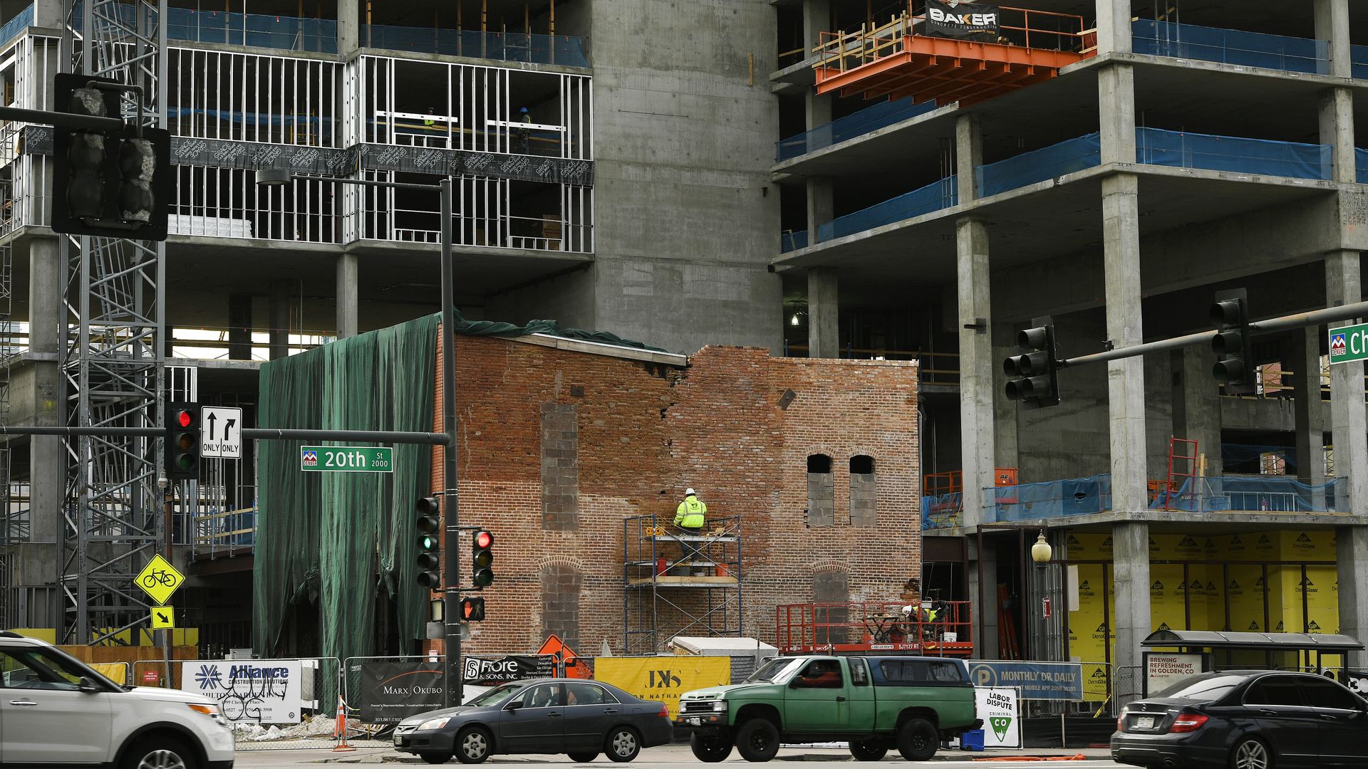 A photo of an apartment building development going up behind an old red-bricked historic building