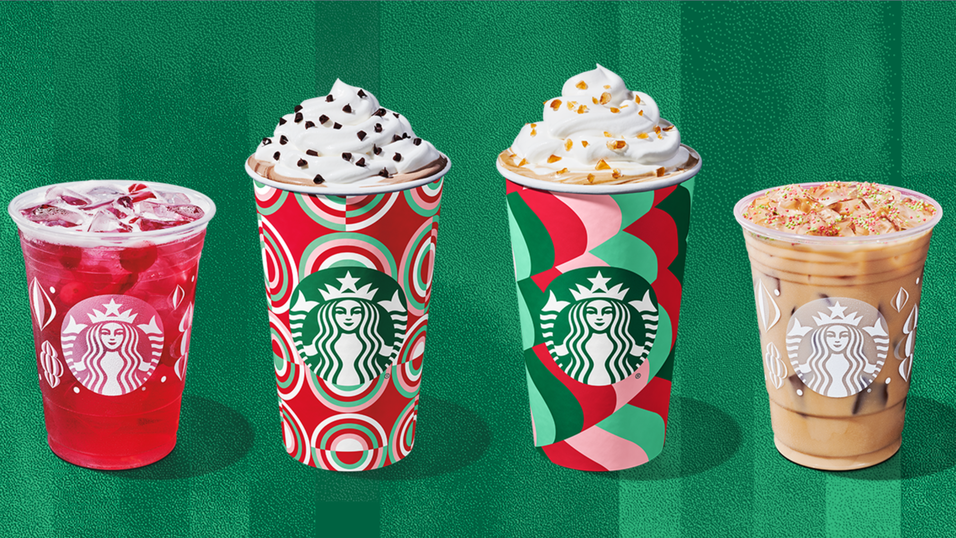 Four Starbucks drinks stand in a row with the two in the middle in colorful paper cups with whipped cream and sprinkles on top, and two iced drinks flanking them, in front of a green background.