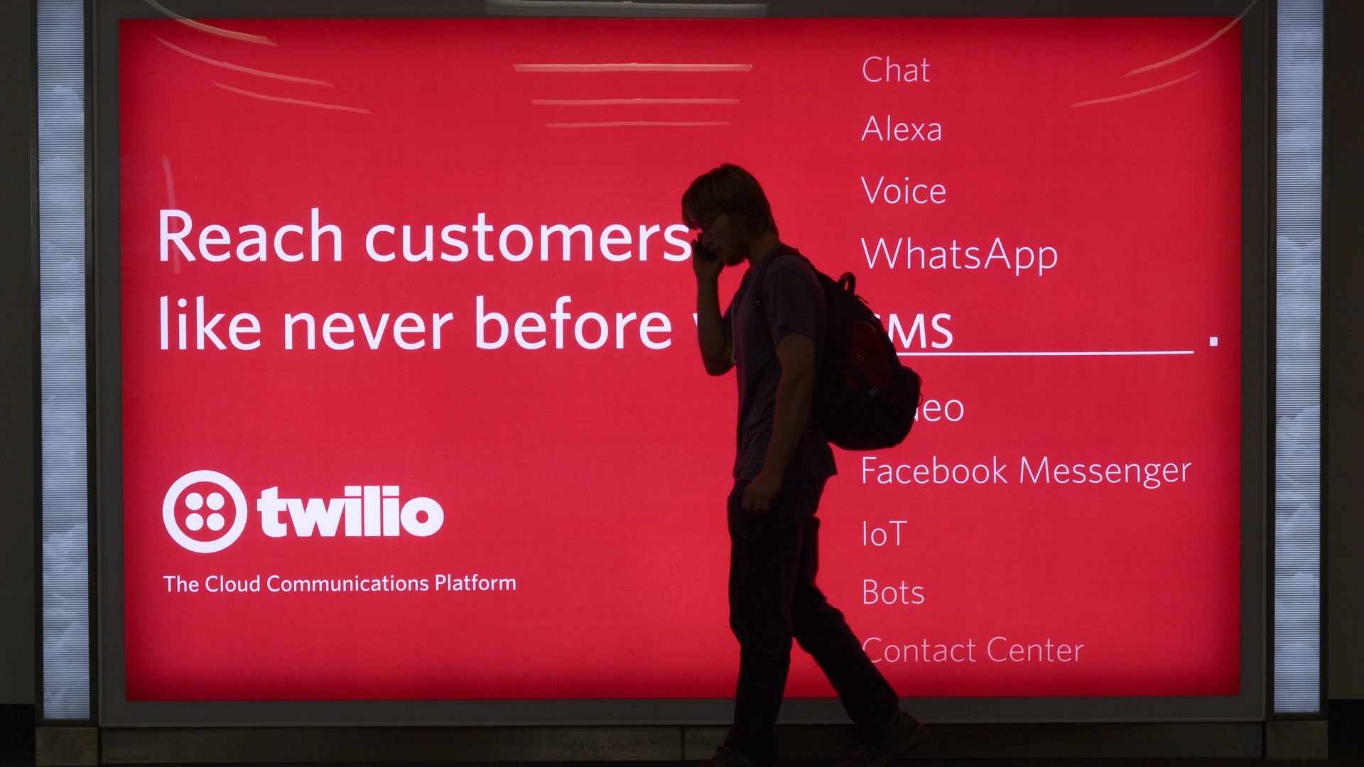 A passenger waiting to board his plane walks in front of a sign advertising Twilio at San Francisco International Airport in San Francisco, California