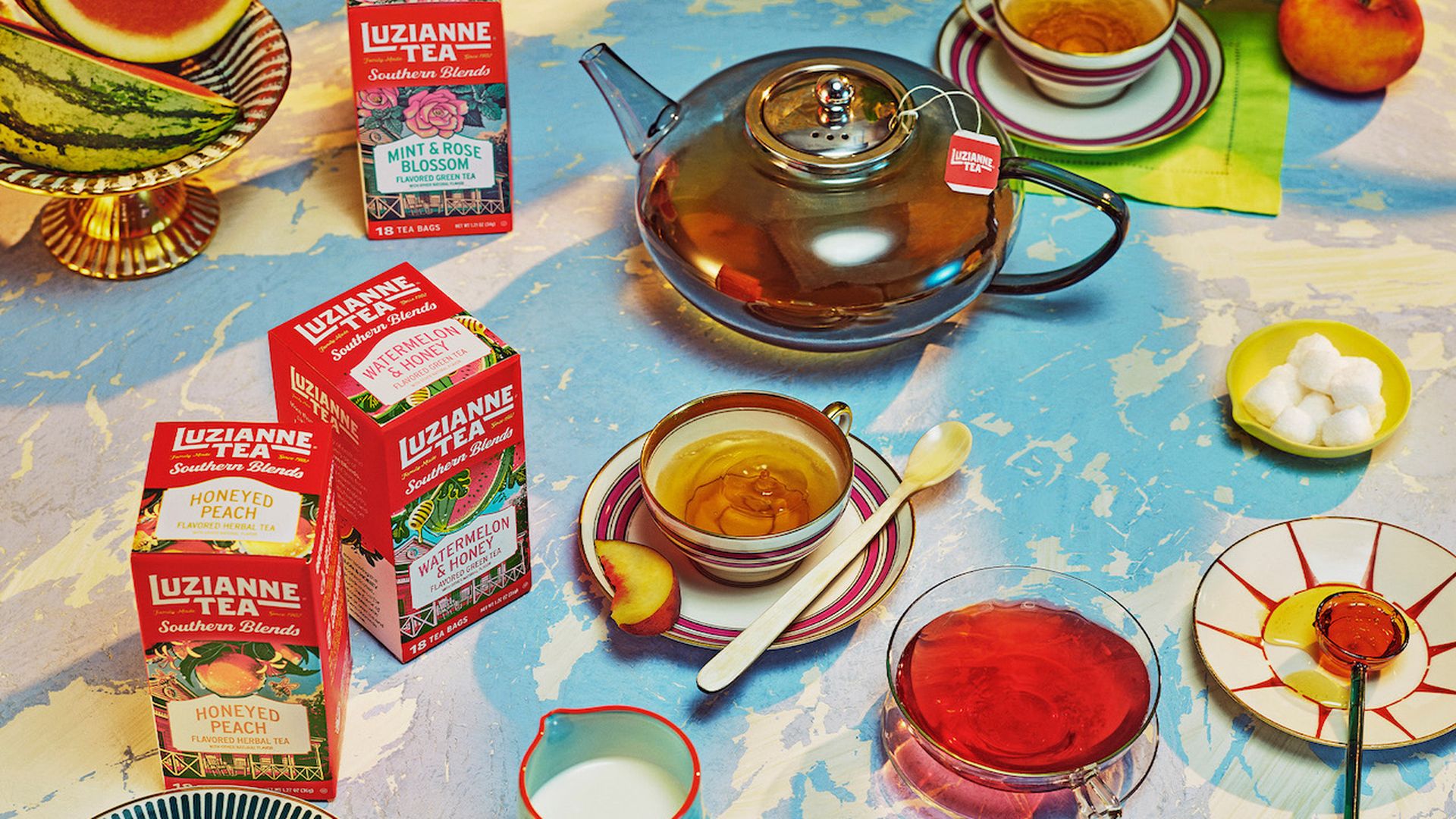 Photo shows boxes of tea on a table with a teapot
