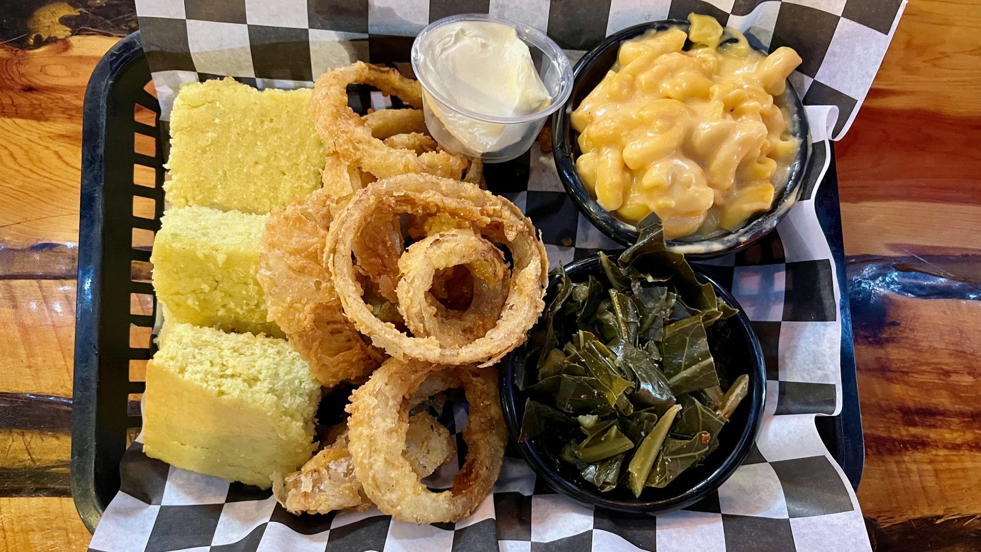 A basket of cornbread, onion rings, greens and macaroni and cheese