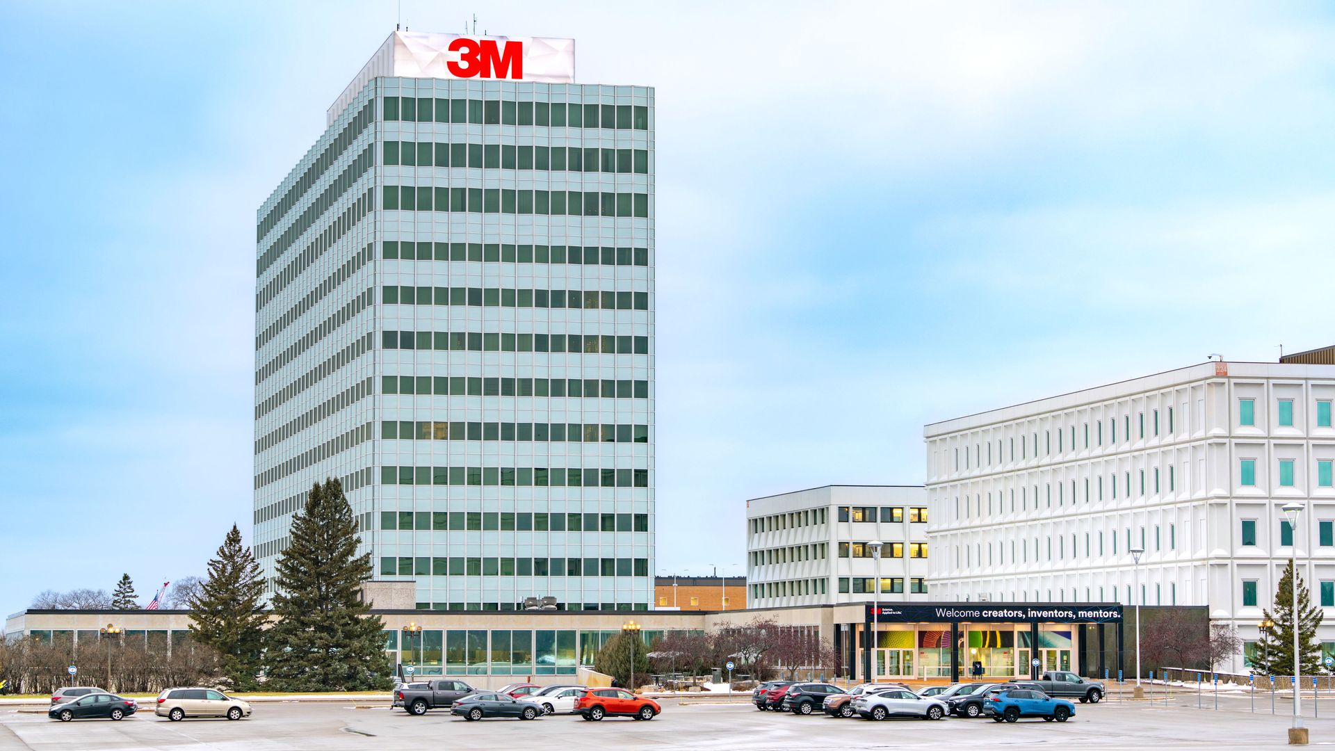 A photo showing 3M's headquarters building with a mostly empty parking lot in the foreground 