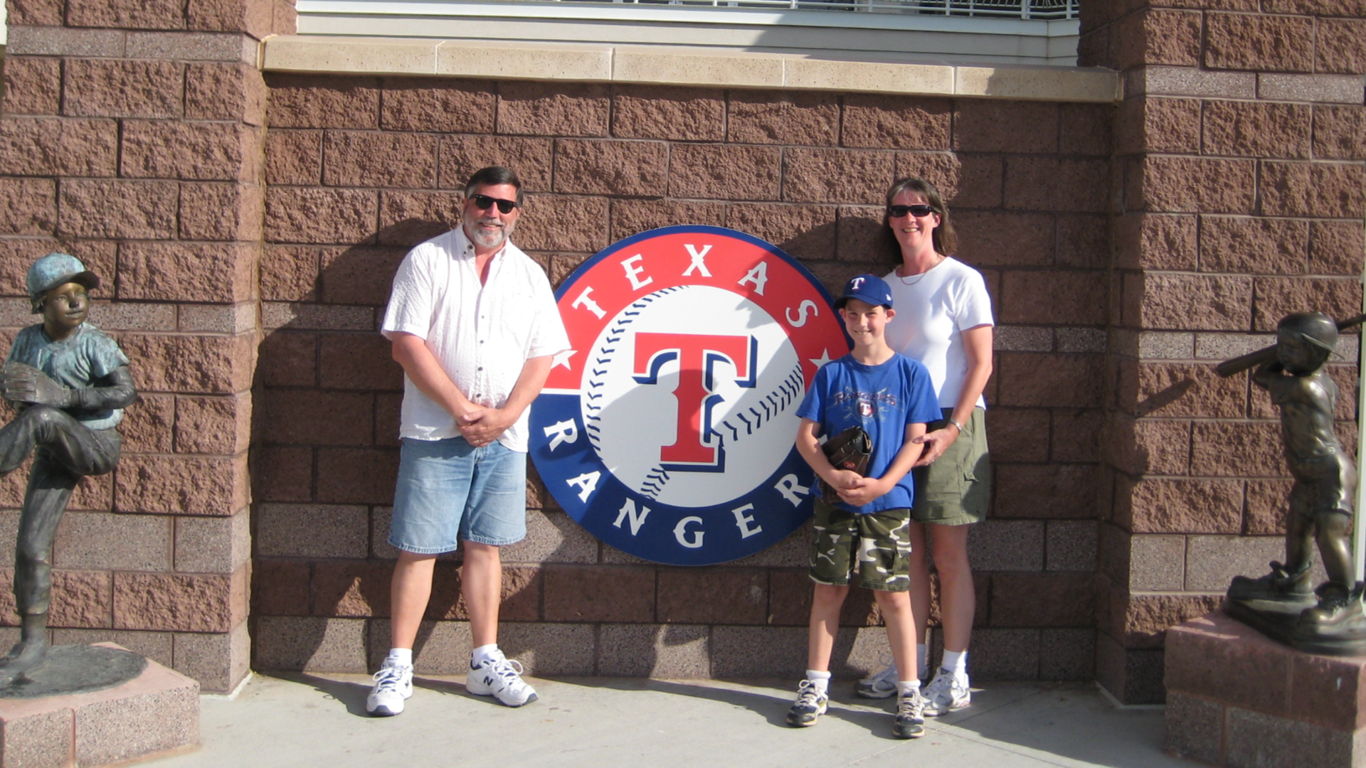 Three people standing in front of a Texas Rangers sign