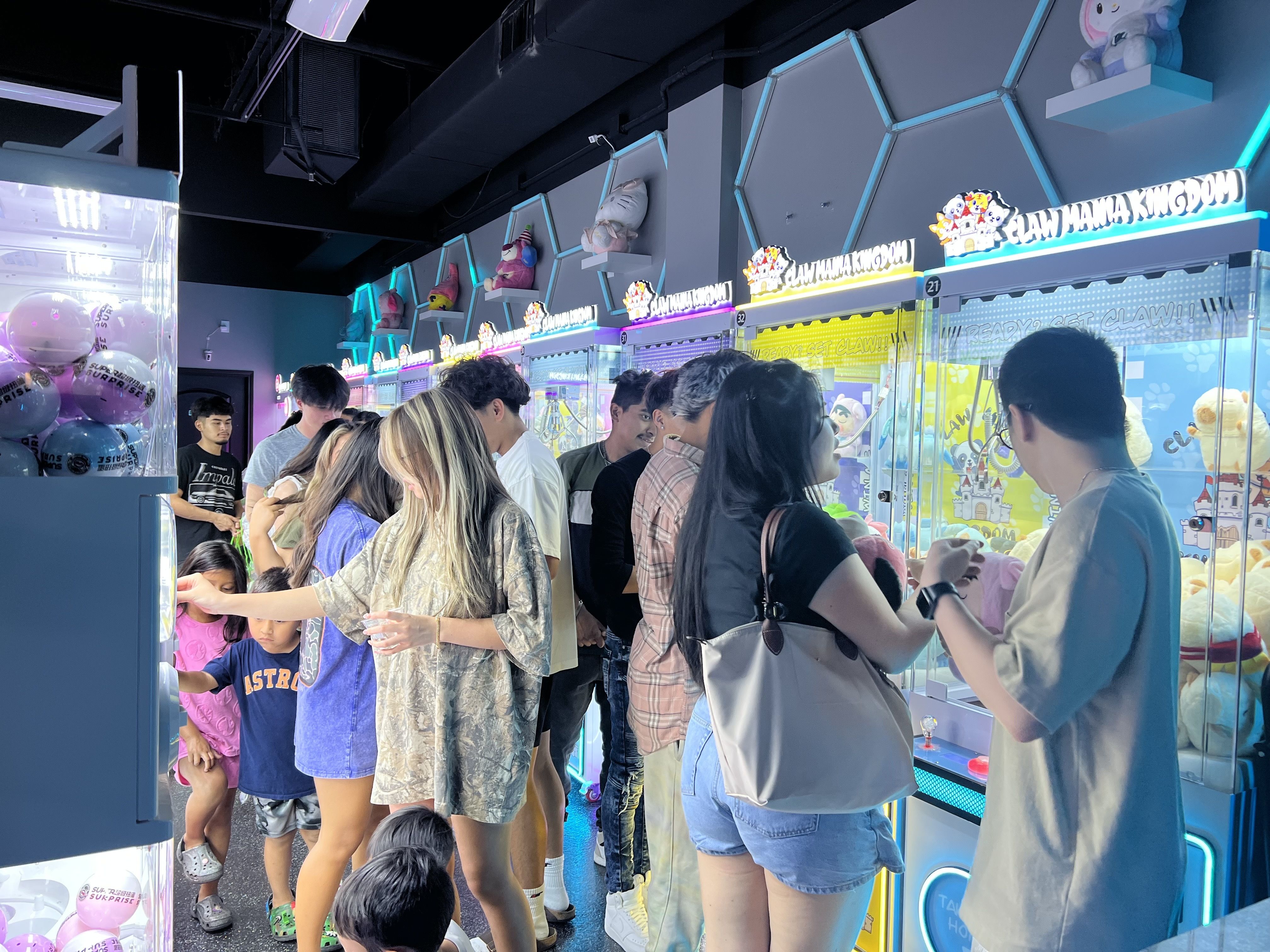 Photo of people playing with claw machines. 