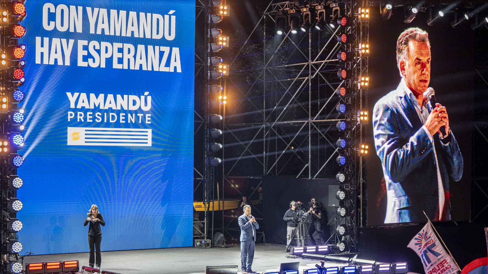 uruguyan presidential candidate Yamandú Orsi stands on a stage with bright lights around him