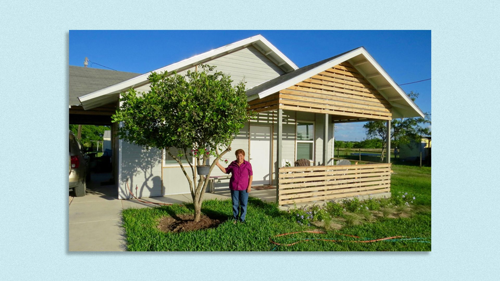 A woman stands in front of a home.