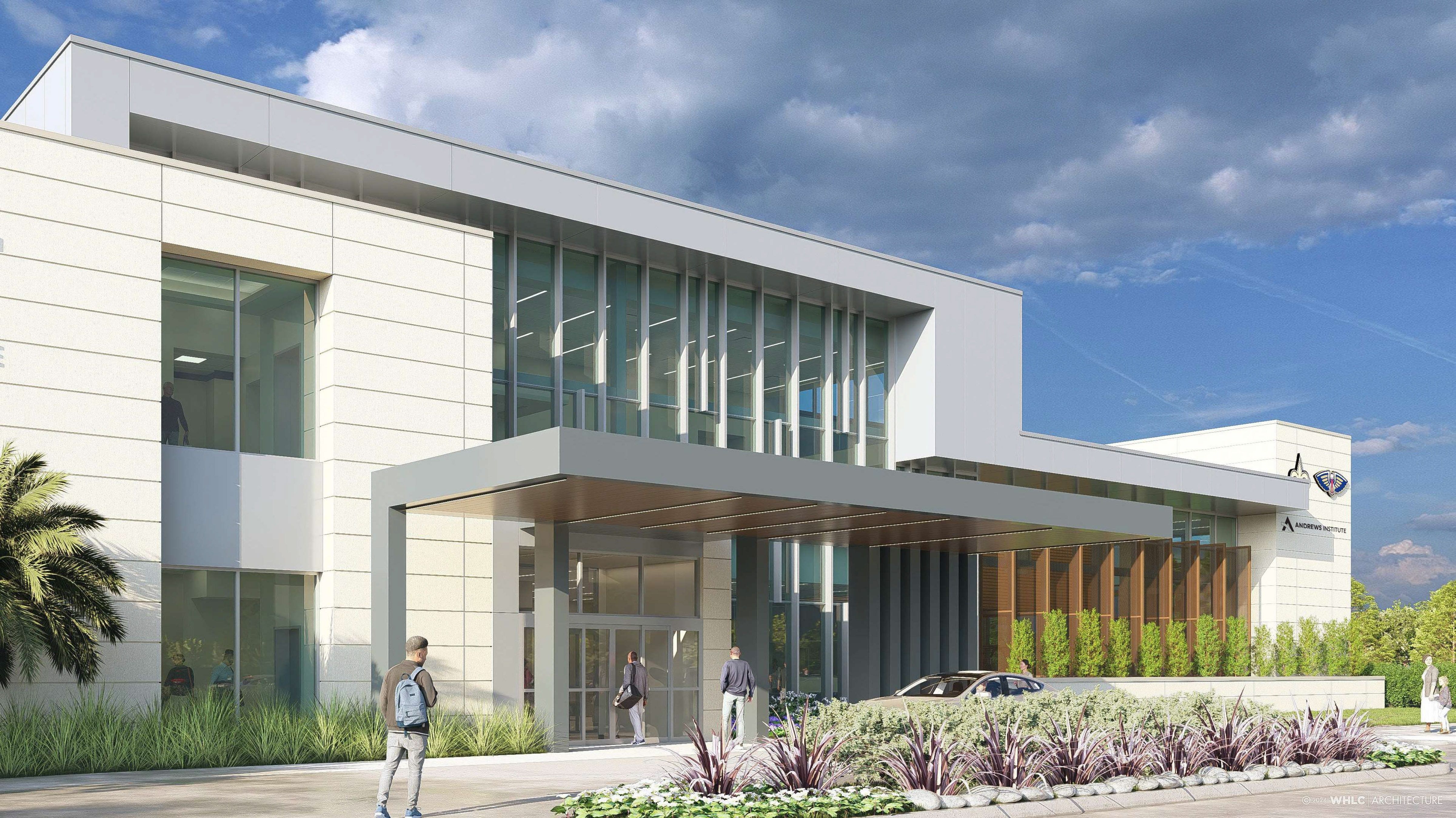 Modern white building with large glass windows under a partly cloudy blue sky. People walk near the entrance with a gray canopy. Landscaping with green plants and purple foliage.