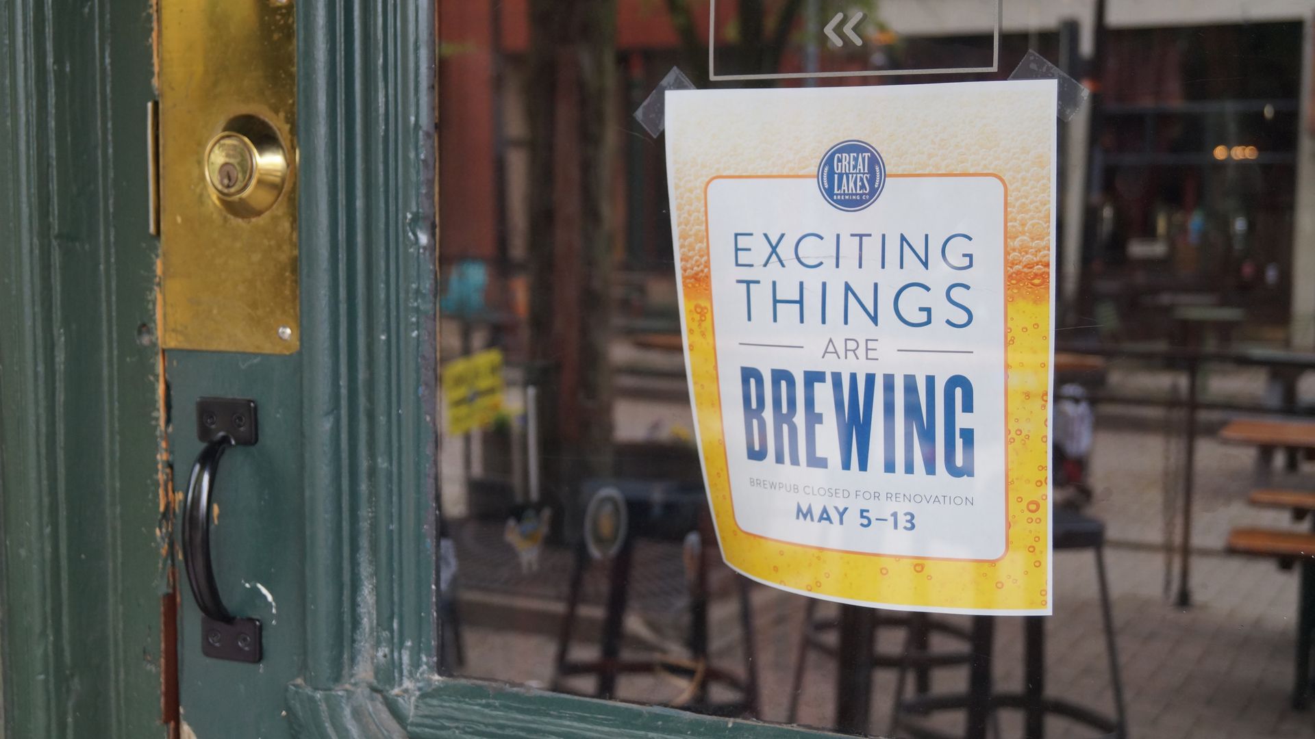 A paper sign in the window of a door reading "Exciting Things are Brewing"