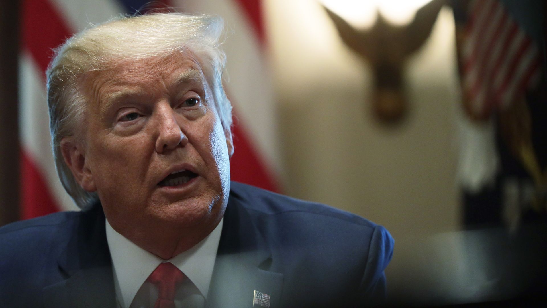 In this image, Trump sits in a suit 