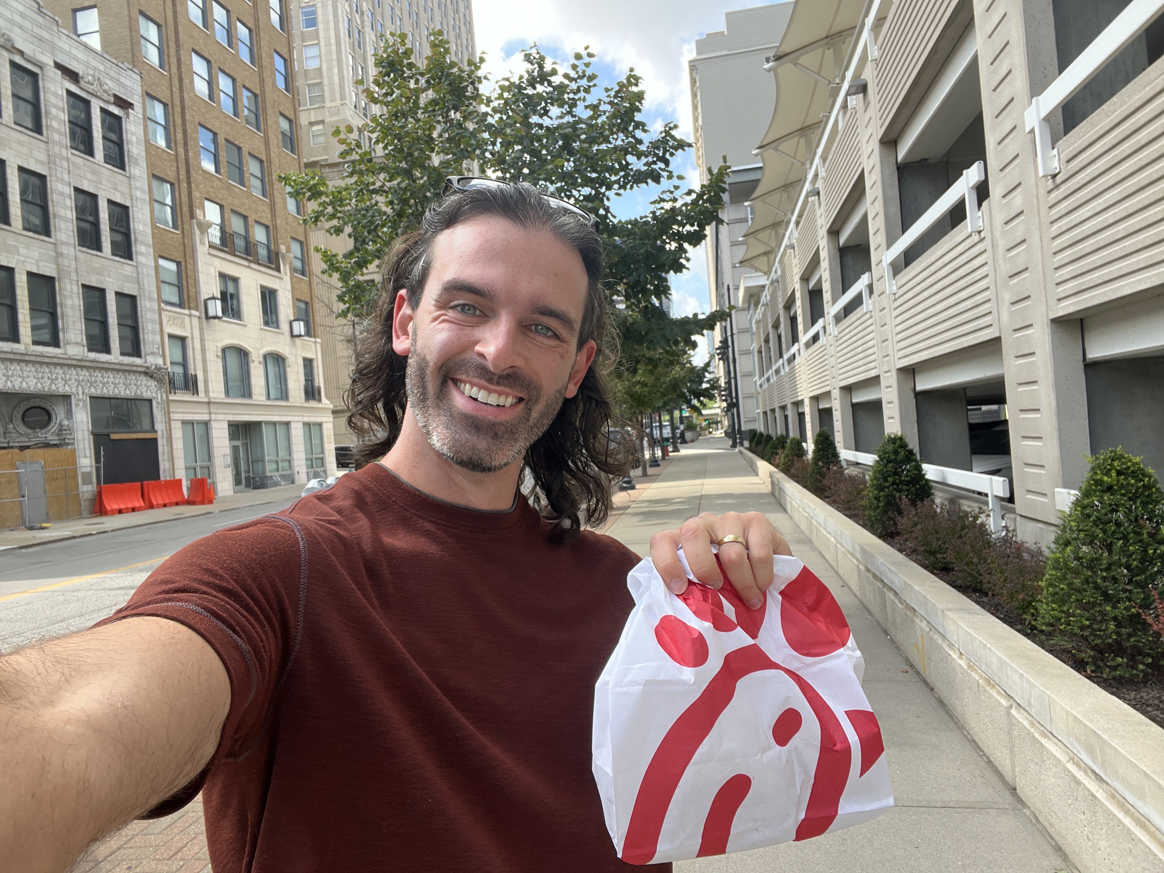 Reporter Travis Meier holds a carryout Chick-fil-A bag while walking on Walnut Street.