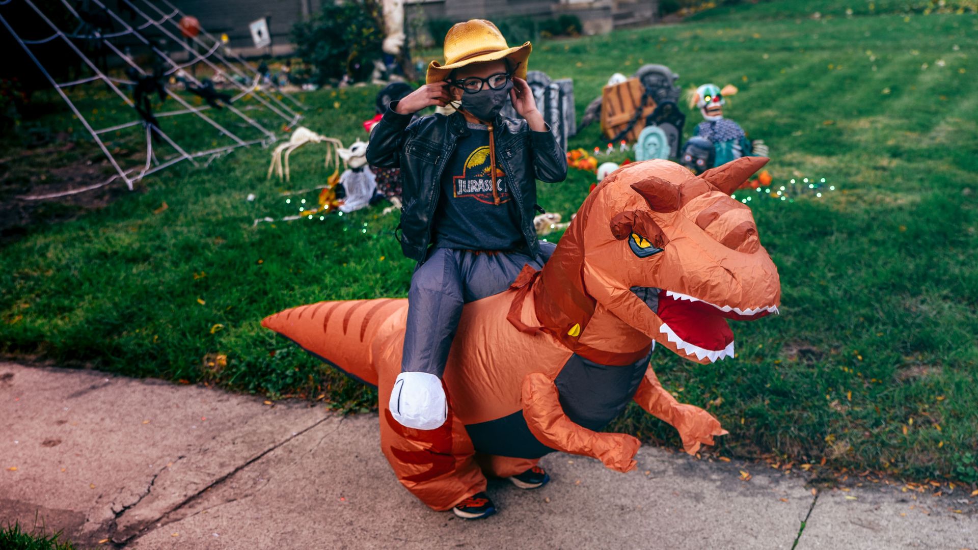 A child wearing a costume that looks like he's riding a dinosaur.