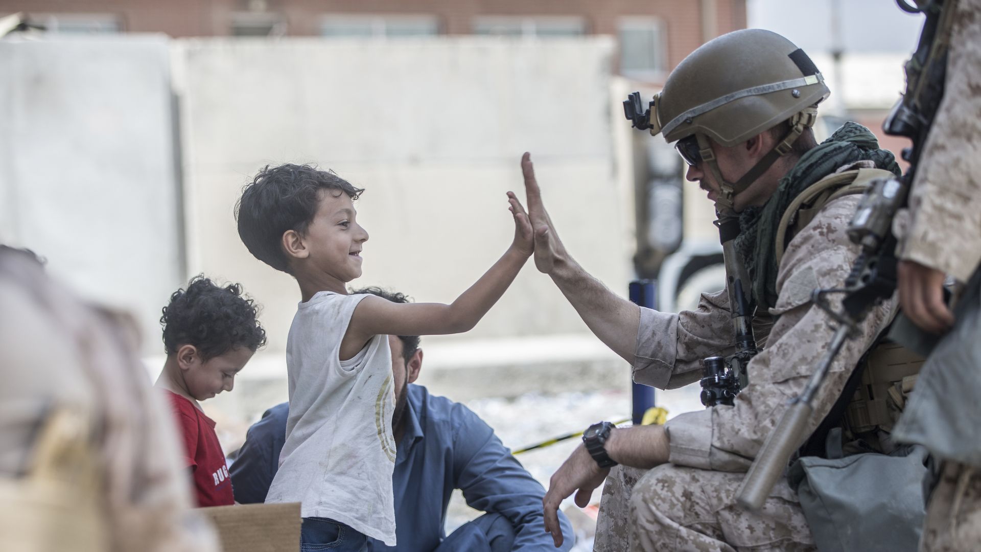 A U.S. Marine high-fives a child at Kabul airport yesterday. Photo: Sgt. Samuel Ruiz/U.S. Marine Corps via AP