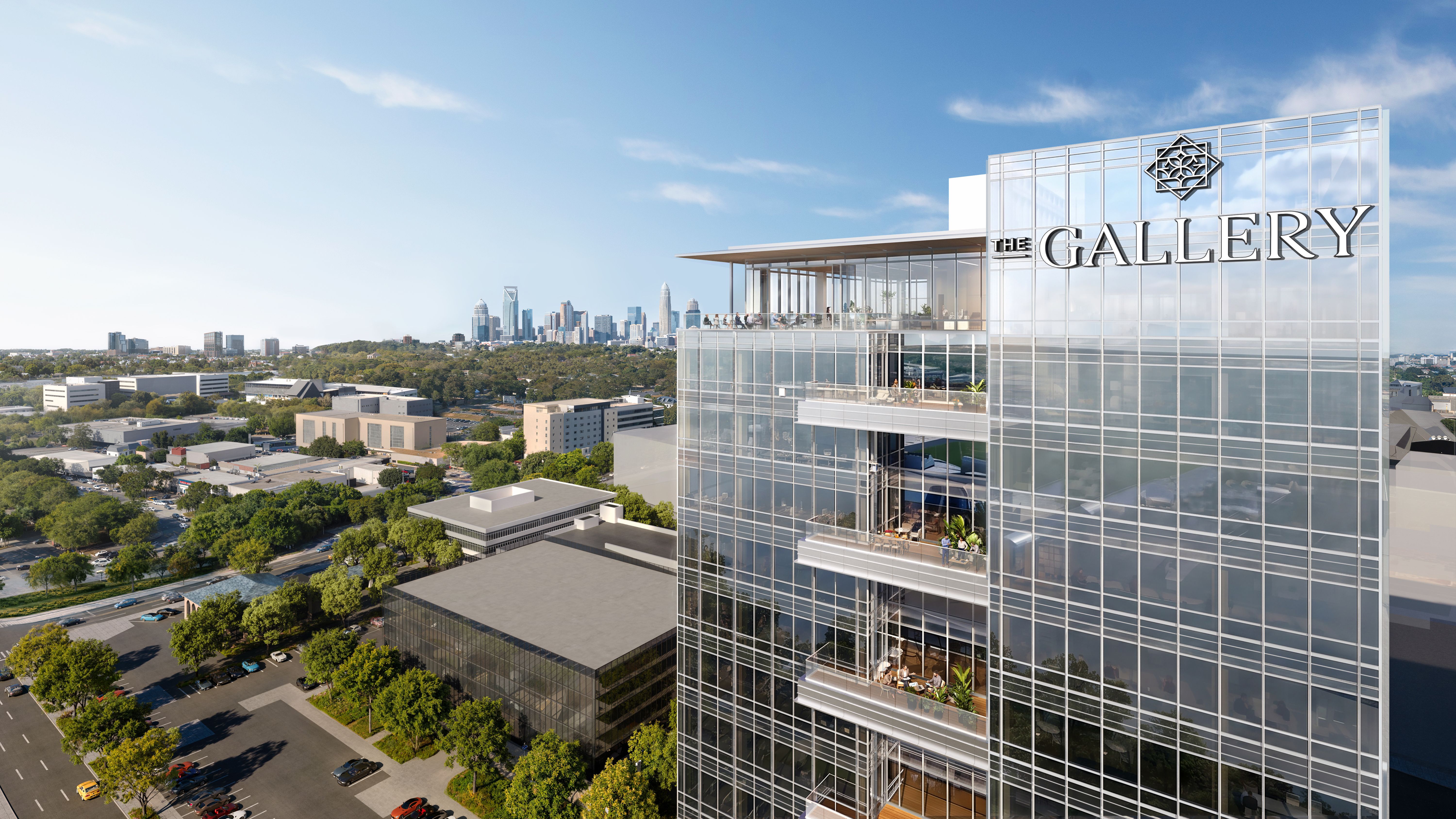 Aerial view of a tall glass building labeled "THE GALLERY" with terraces and people on balconies, set against a clear blue sky and distant city skyline.
