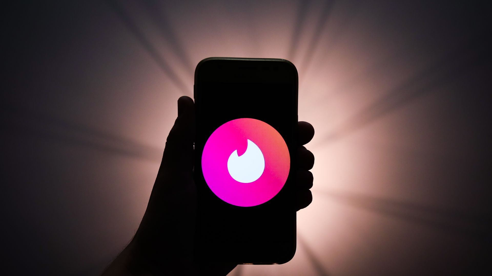 Photo illustration of a Tinder logo displayed on a phone screen.