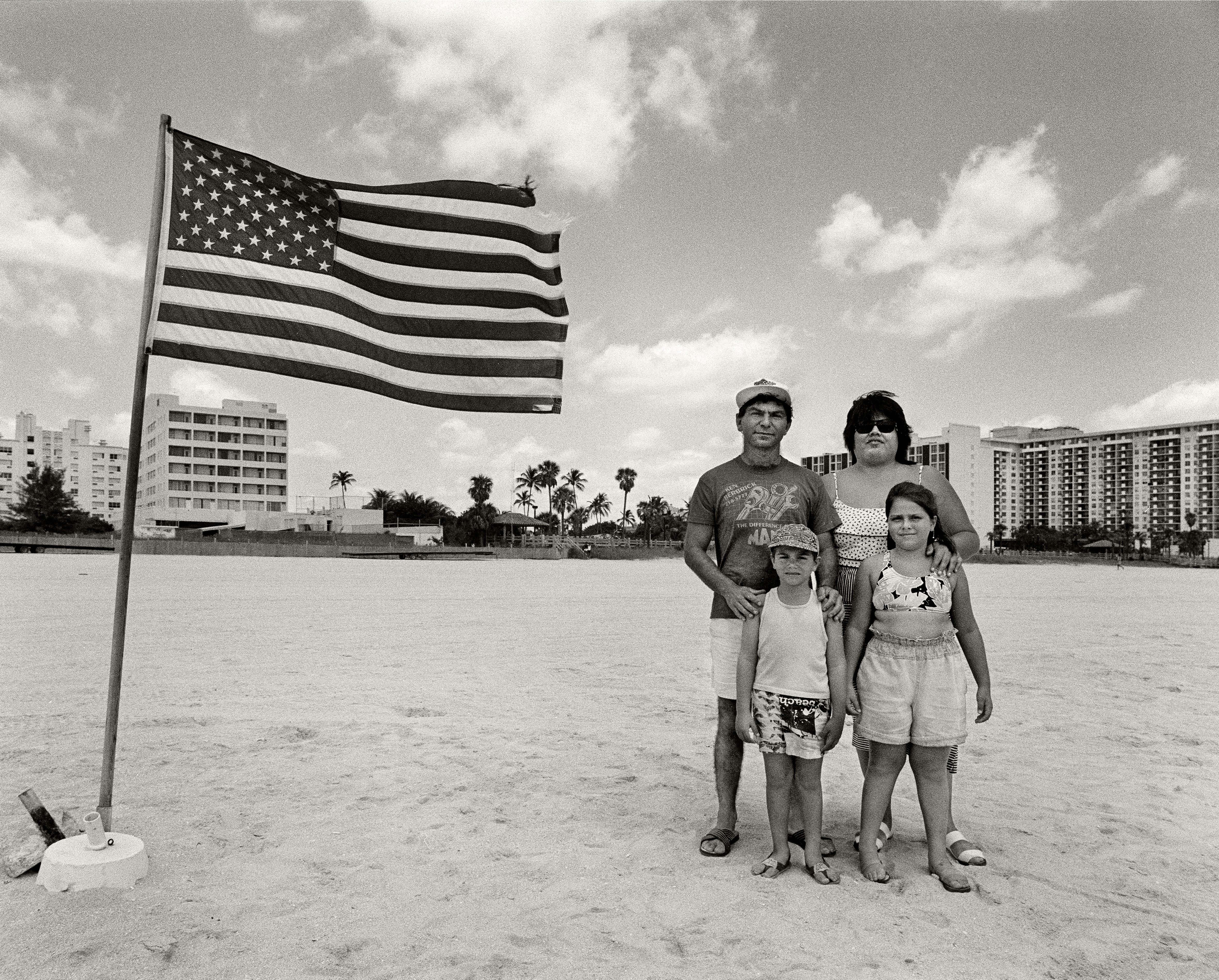 Hispanic family posing next to the American Flag on Miami Beach in 1989.